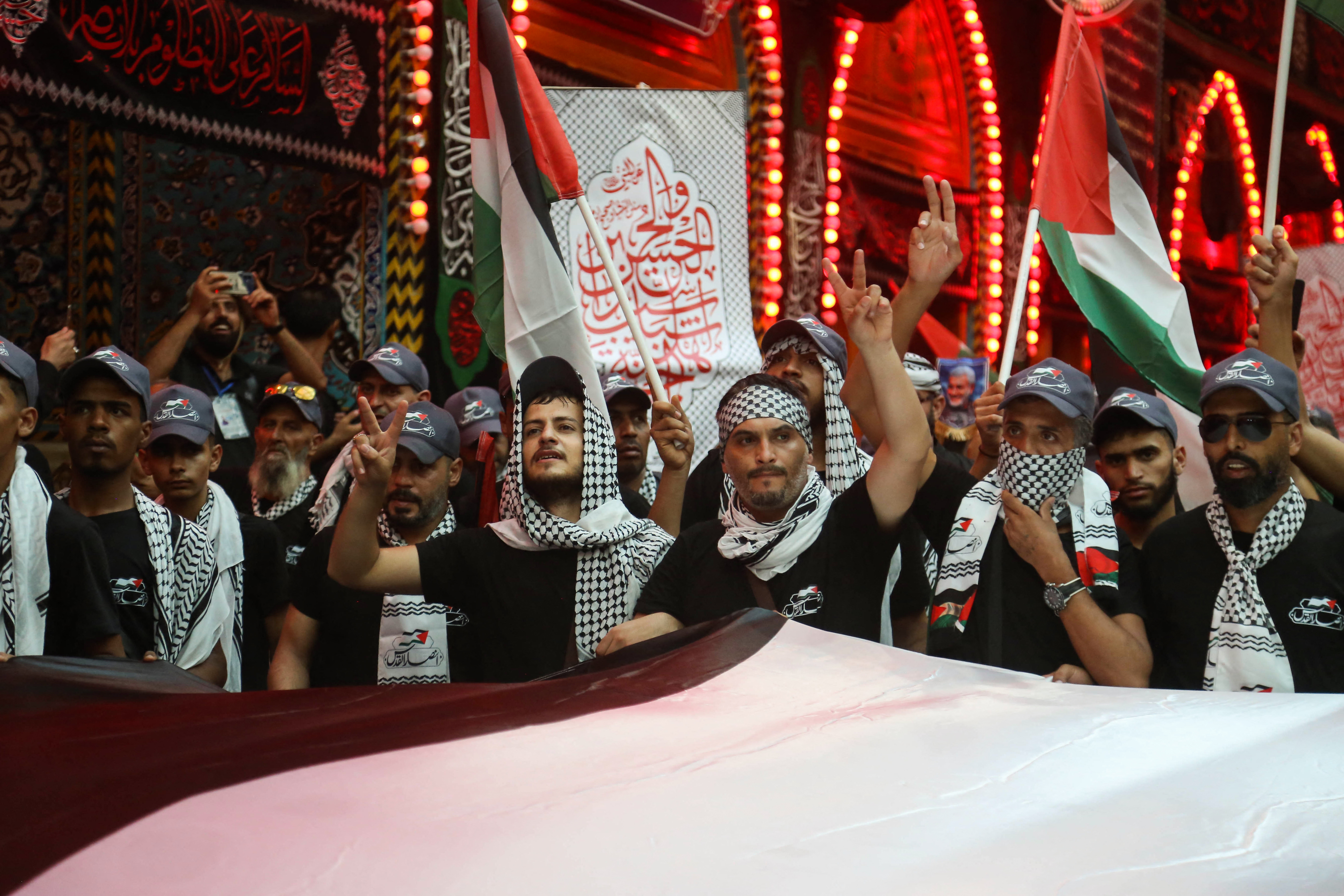 Devotees lift flags of Palestine and wear traditional Palestinian keffiyeh scarves to express support for Gaza, as they take part in a mourning ritual at the shrine of Imam Abu Al-Fadl al-Abbas in Iraq's Karbala on August 24, 2024, as Shiite Muslim pilgrims gather in the holy shrine city for the Arbaeen commemorations that mark the end of the 40-day mourning period for the seventh century killing of the Prophet Mohamed's grandson Imam Hussein Bin Ali. (Photo by Mohammed SAWAF / AFP)