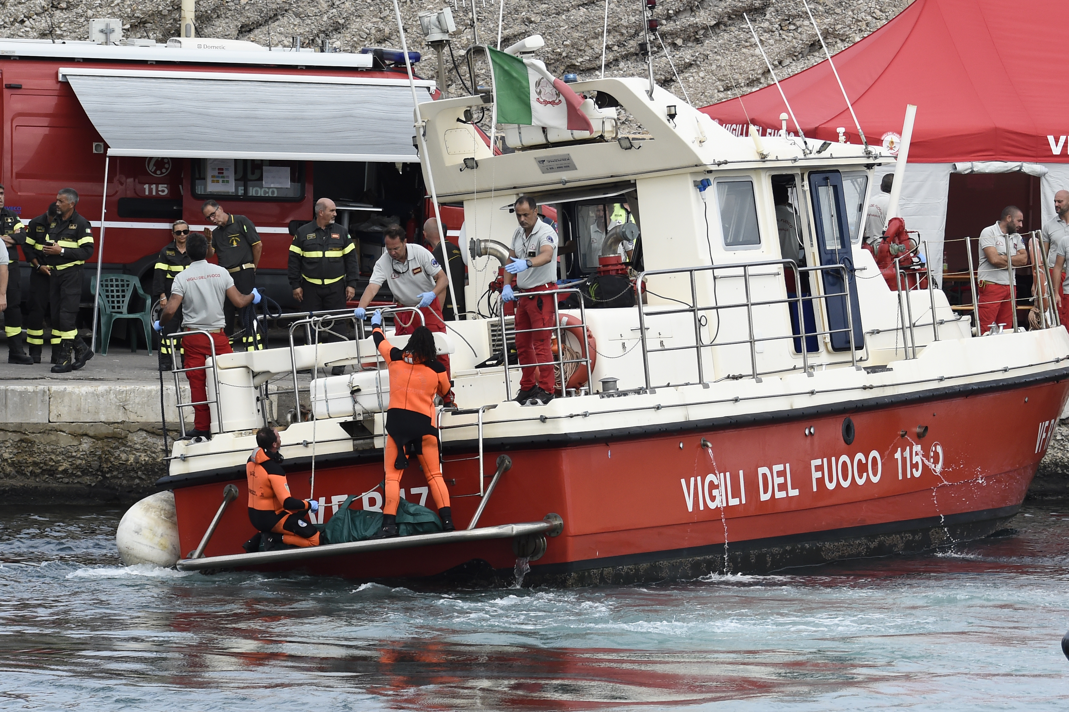Italian Firefighters scuba divers bring ashore in a green bag the body of one of the victims of the UK flag vessel Bayesian, Wednesday, Aug. 21, 2024. The sail yacht was hit by a violent sudden storm and sunk early Monday, while at anchor off the Sicilian village of Porticello near Palermo, in southern Italy. (AP Photo/Salvatore Cavalli)