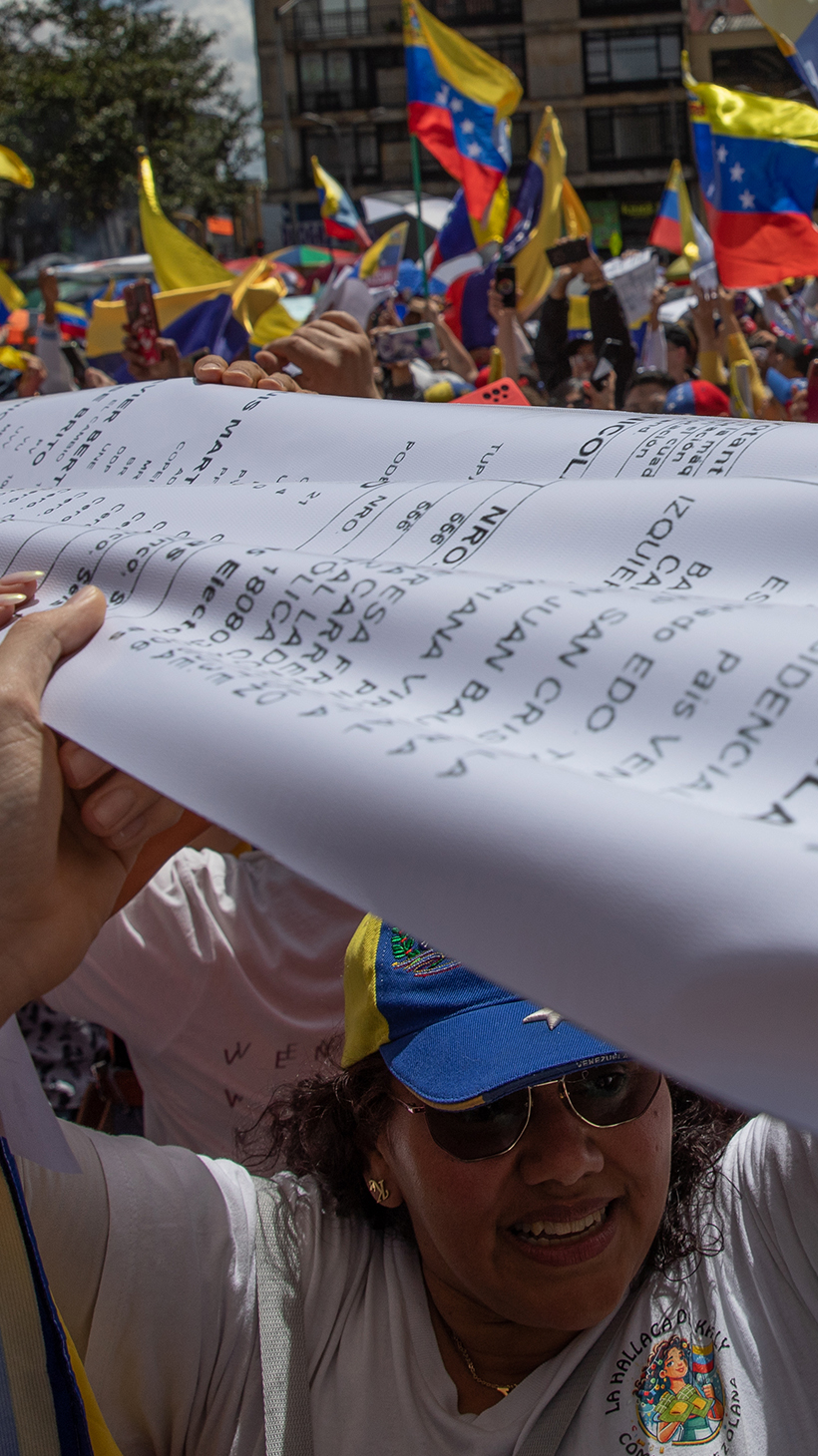 Venezuelan protesters in Bogota stretch a giant print-out of the voter tallies across the crowd, while others wave Venezuelan flags.