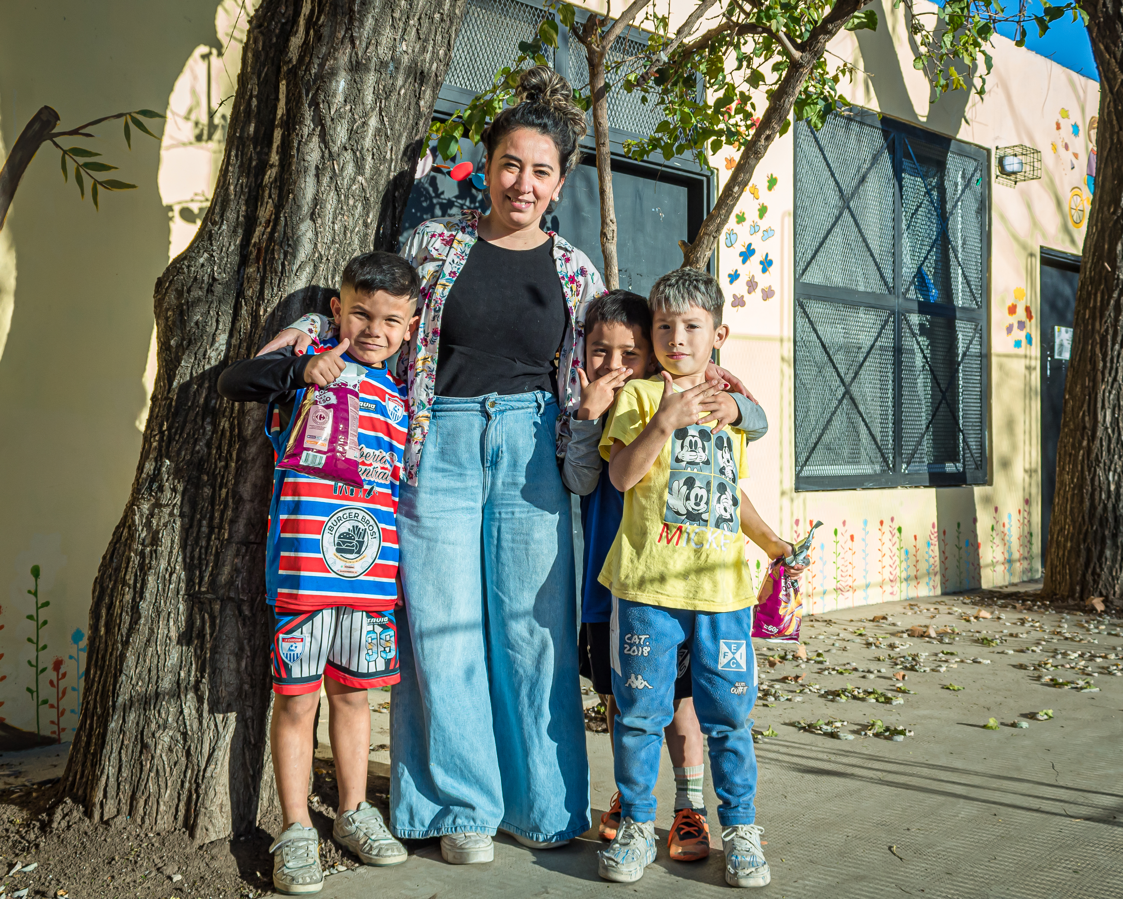 Gisela Perez poses in front of a tree with her arms around her three children.