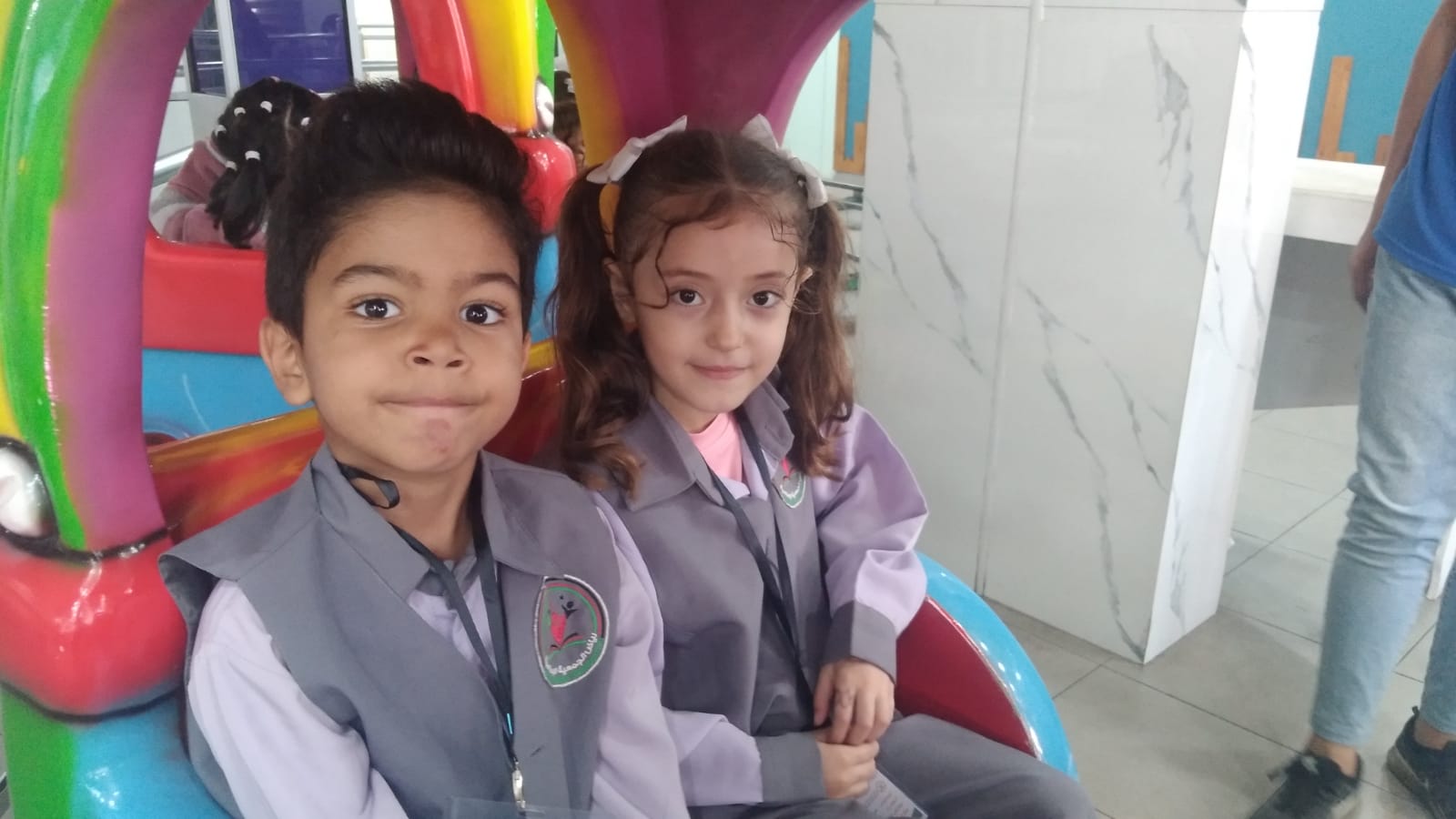 A photo of a little boy and a girls sitting on a children's ride