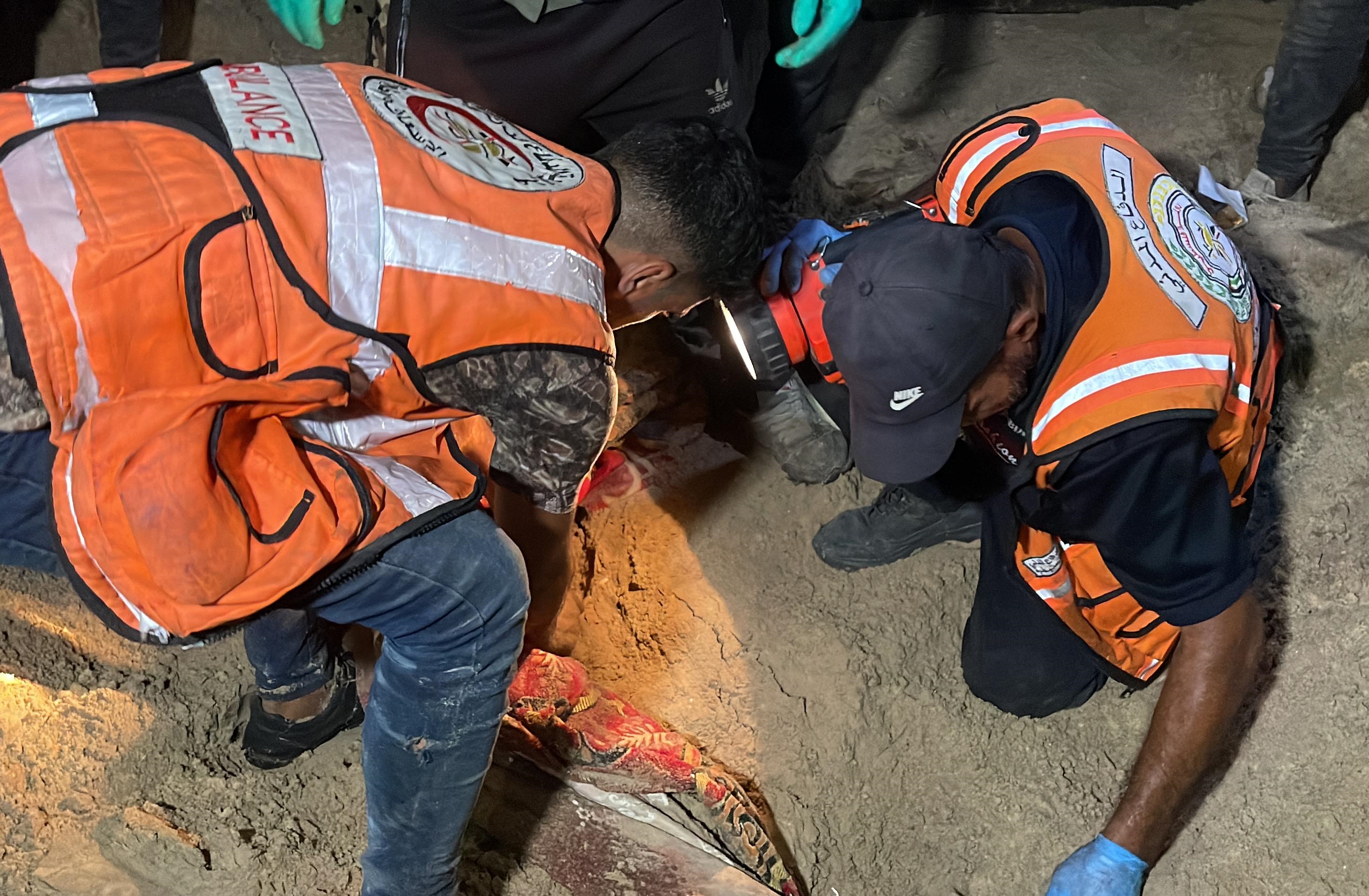Rescuers searching the sandy ground for victims and survivors