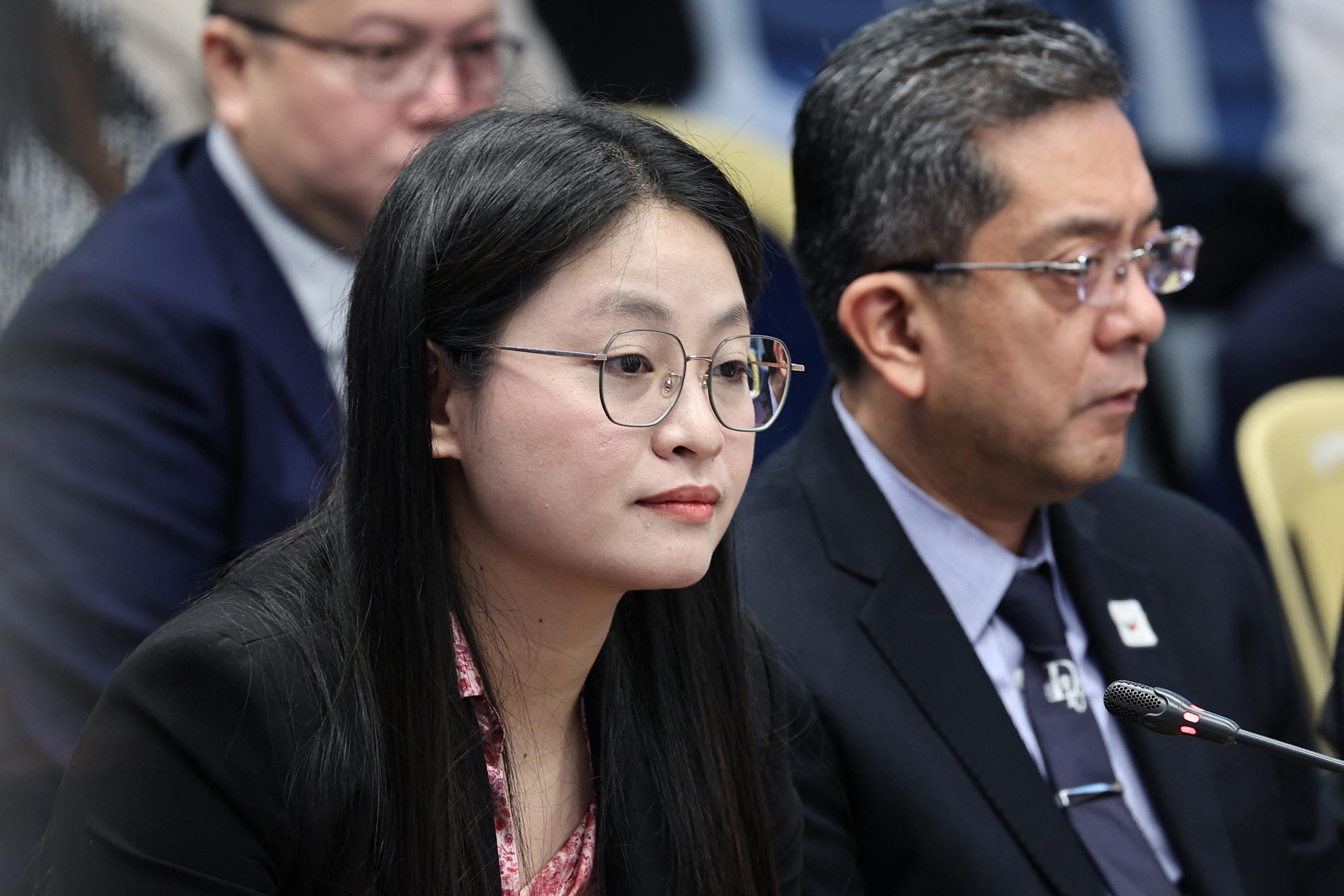 Alice Guo seated at a Senate hearing, She has dark long hair and glasses. She is wearing black.