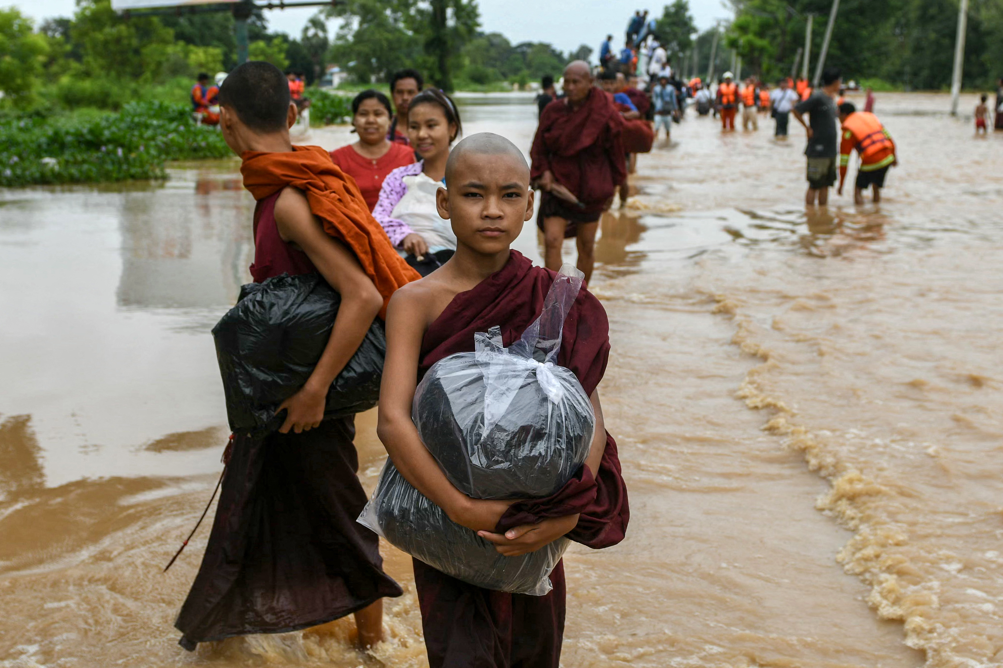 Young monks walking through flood water in Myanmar's Bago region