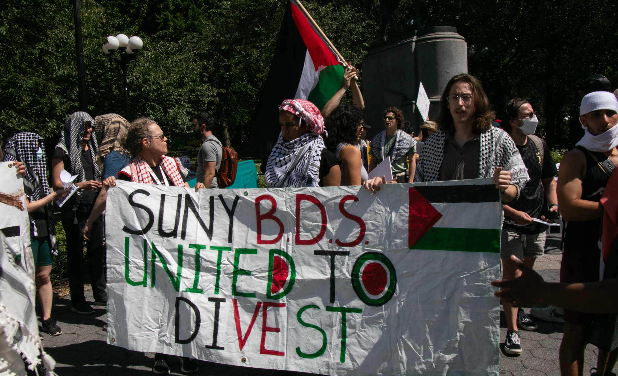 Protesters at SUNY hold up a banner calling on their university to divest.