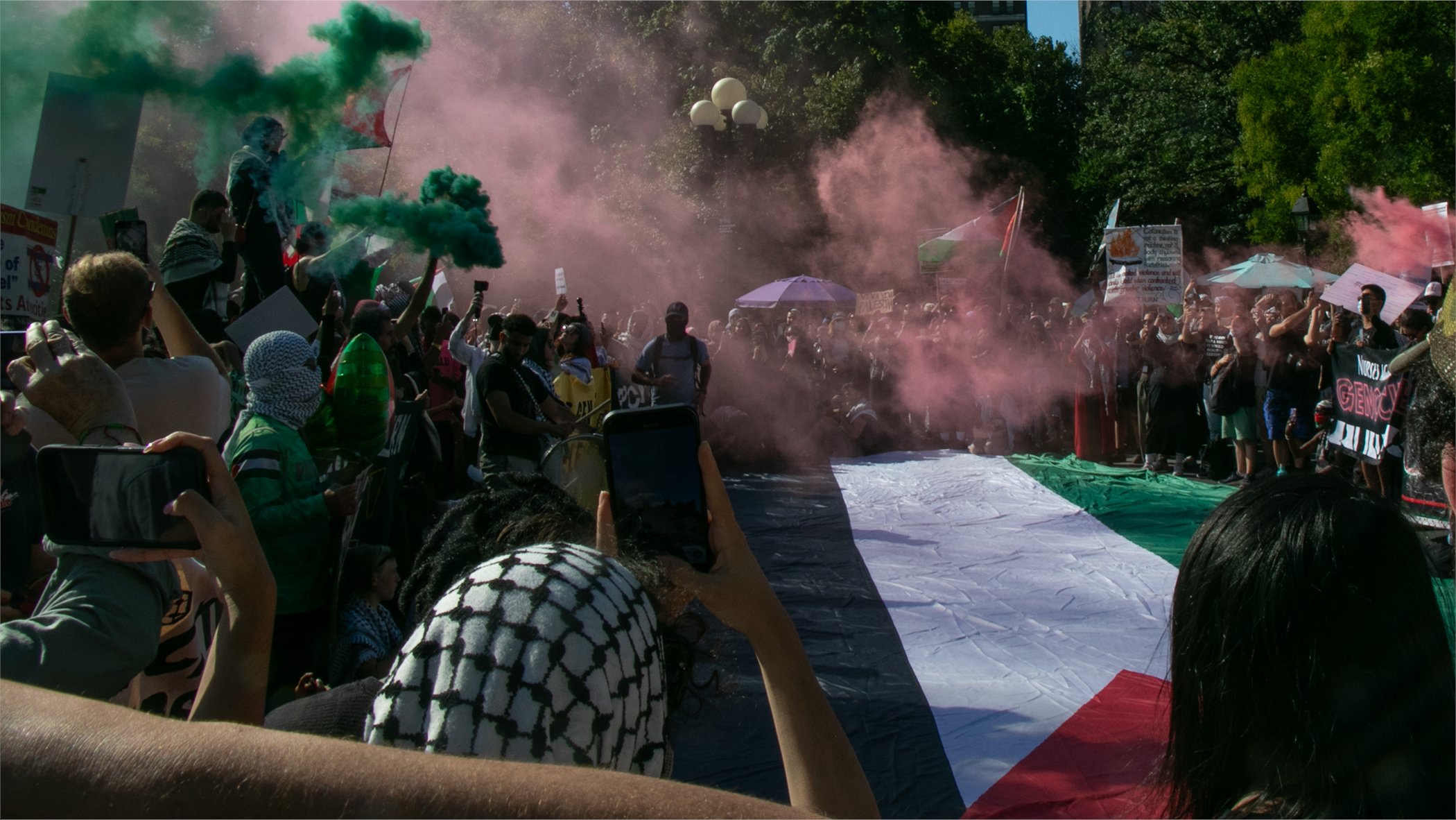 Protesters in New York City carry Palestinian flags, and a red mist is in the air.