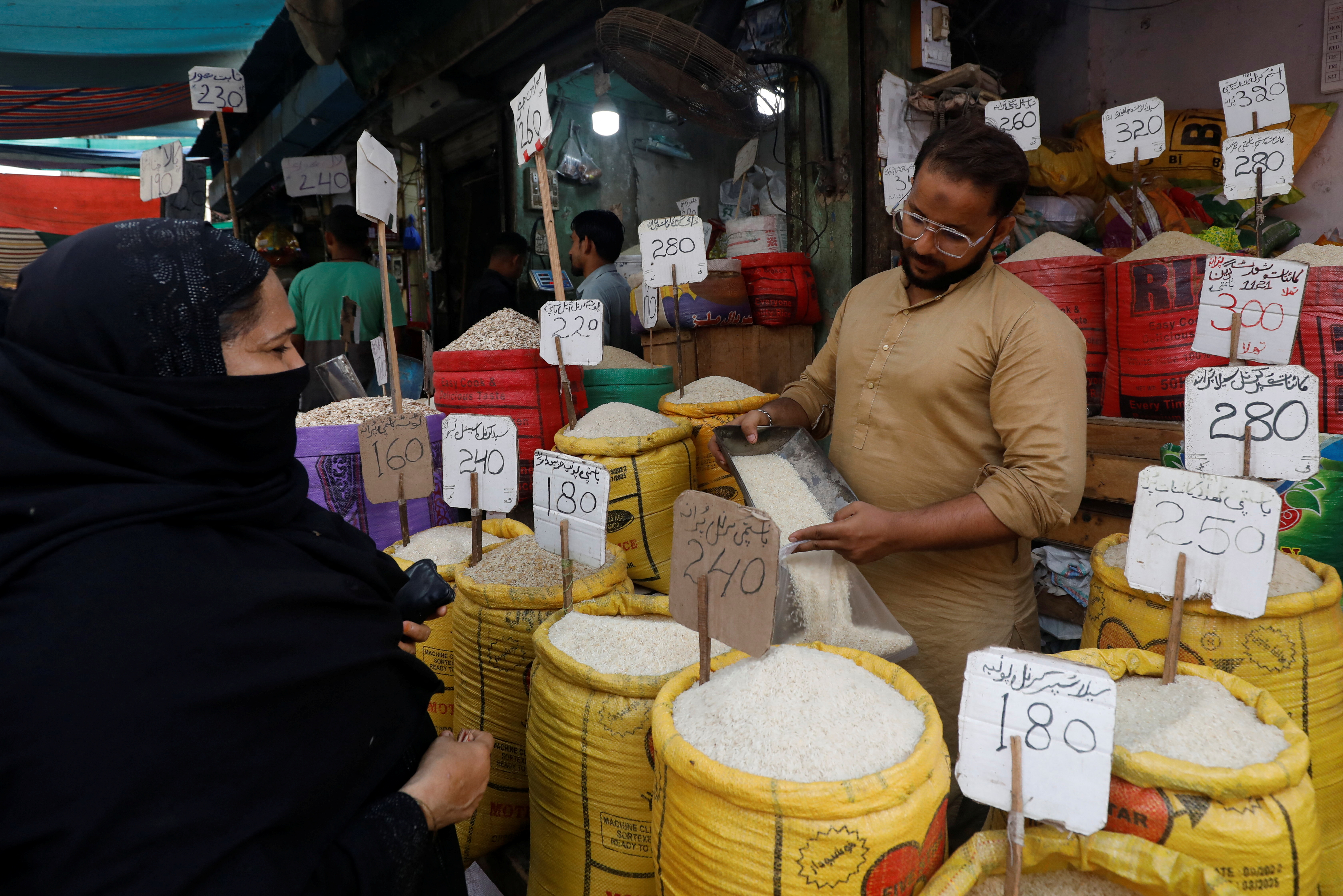 A shopkeeper fills a bag of rice for a customer at a shop along a market in Karachi, Pakistan, June 9, 2023. REUTERS/Akhtar Soomro