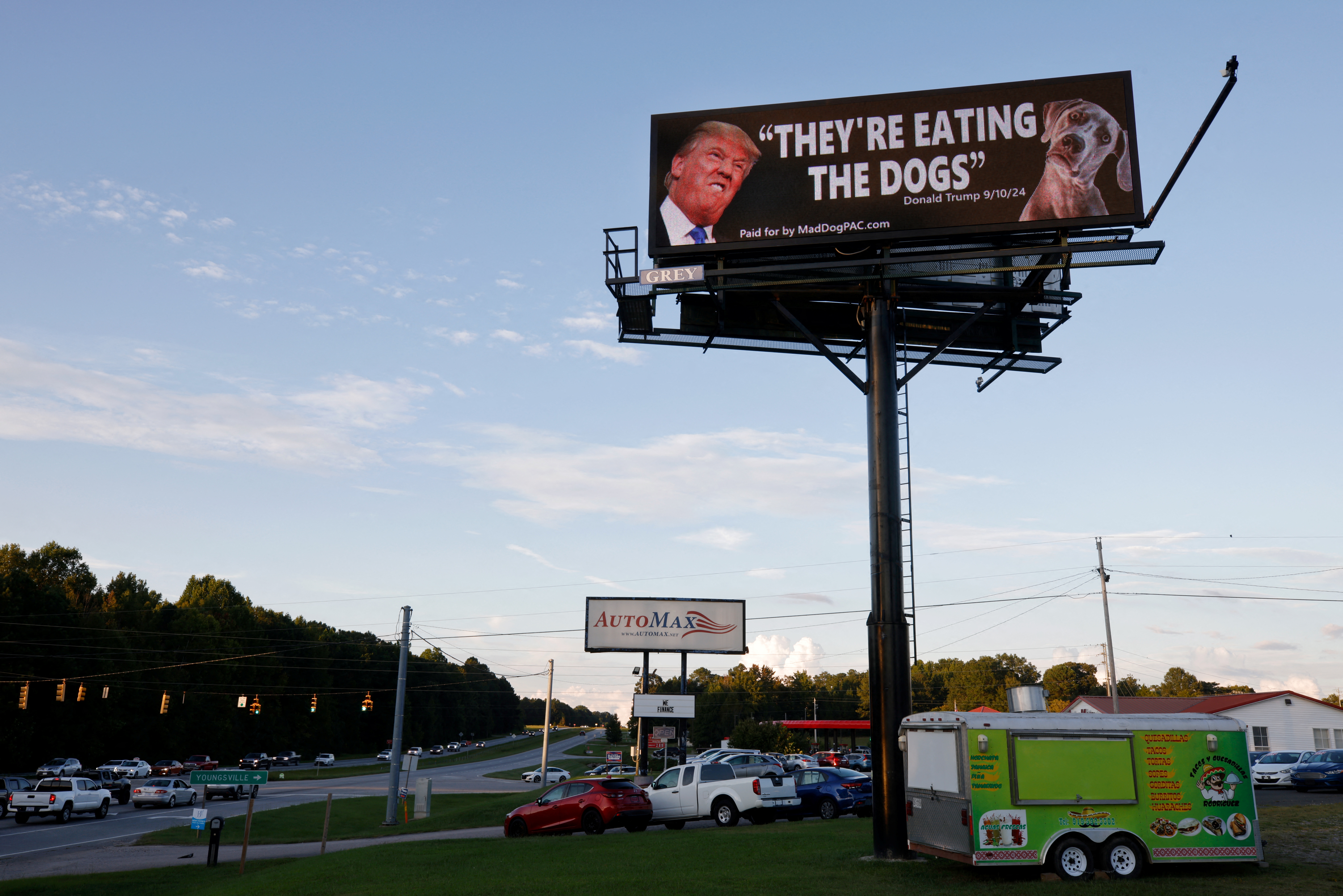 A billboard features Donald Trump's face next to a dog's, with the quote, "They're eating the dogs"