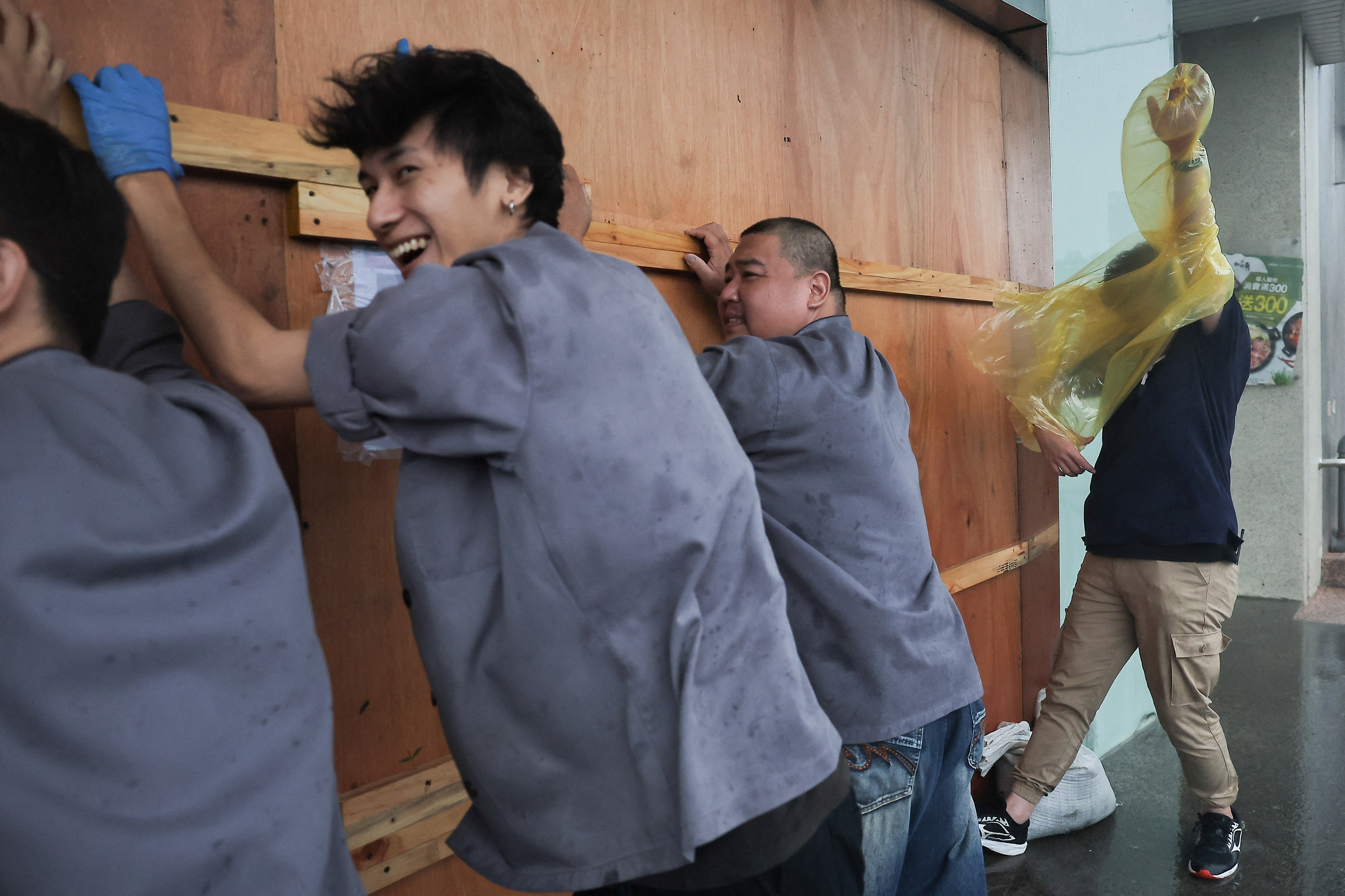 Members of the hotel staff protect the hotel front door as Typhoon Krathon approaches, in Kaohsiung, Taiwan October 3