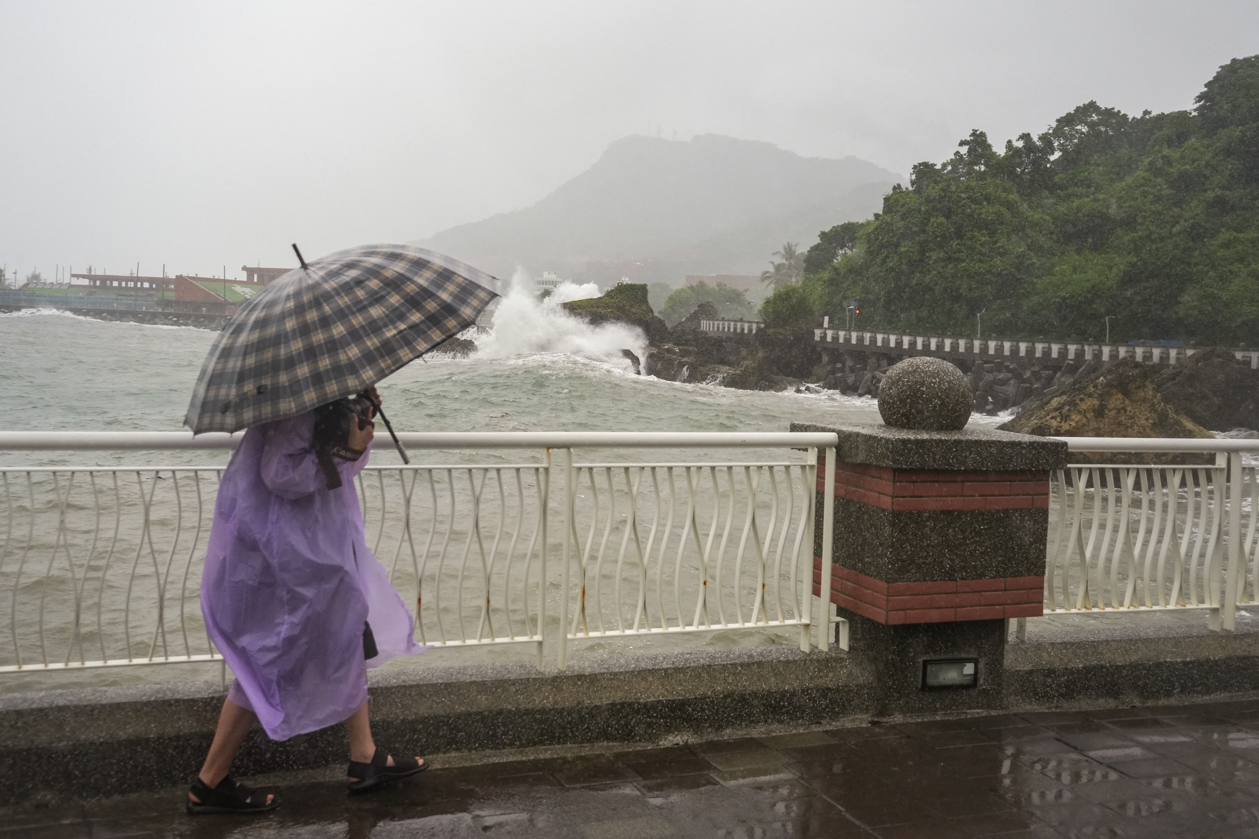 A photographer walks along the coast at Sizihwan beach in Kaohsiung on October 2