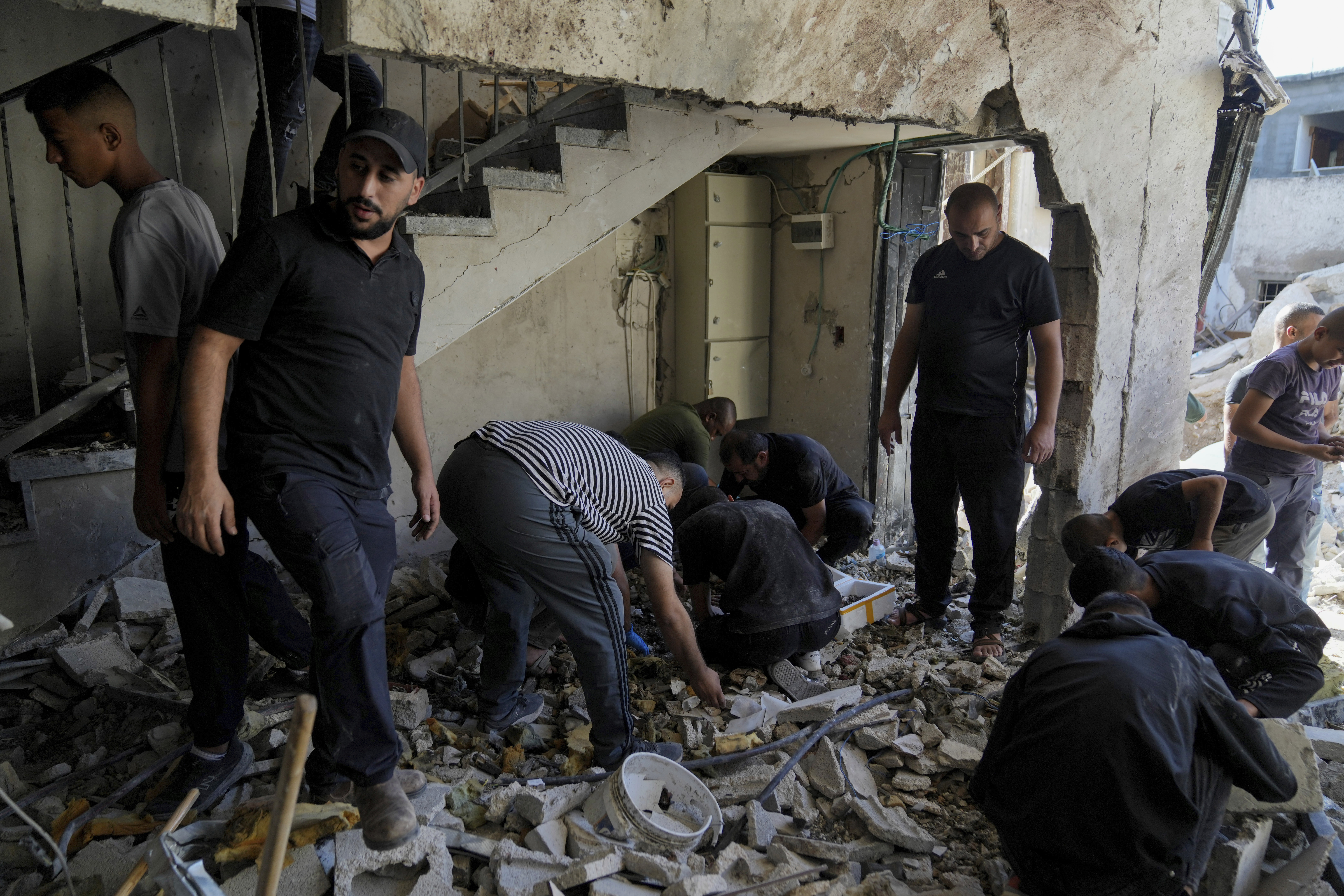 Palestinians examine the damage following an Israeli airstrike in the West Bank city of Tulkarem, which Palestinian health officials say killed 18 people and the Israeli military says took out a Hamas leader, on Friday