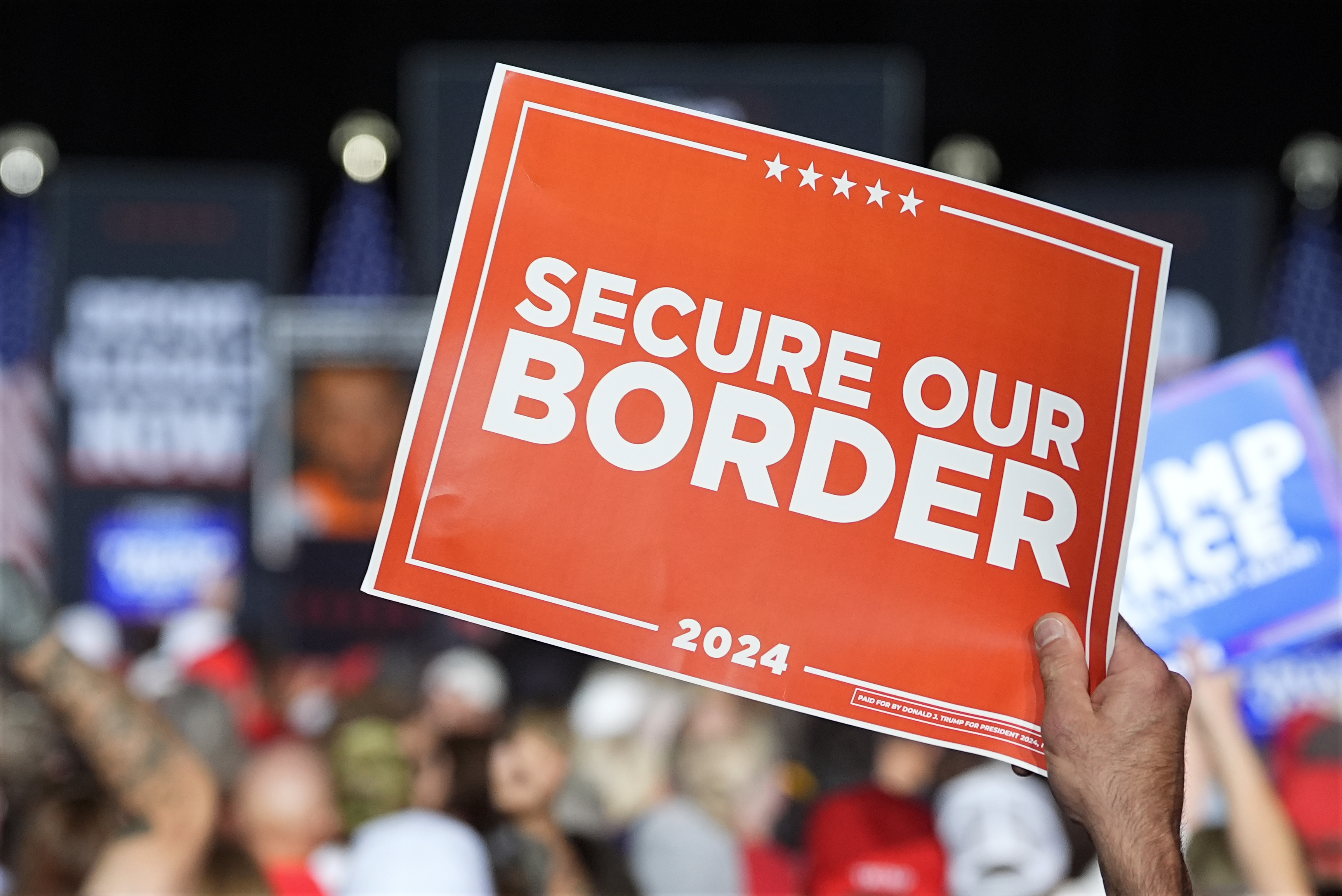 A Trump supporter holds up a sign that reads, "Secure Our Border."