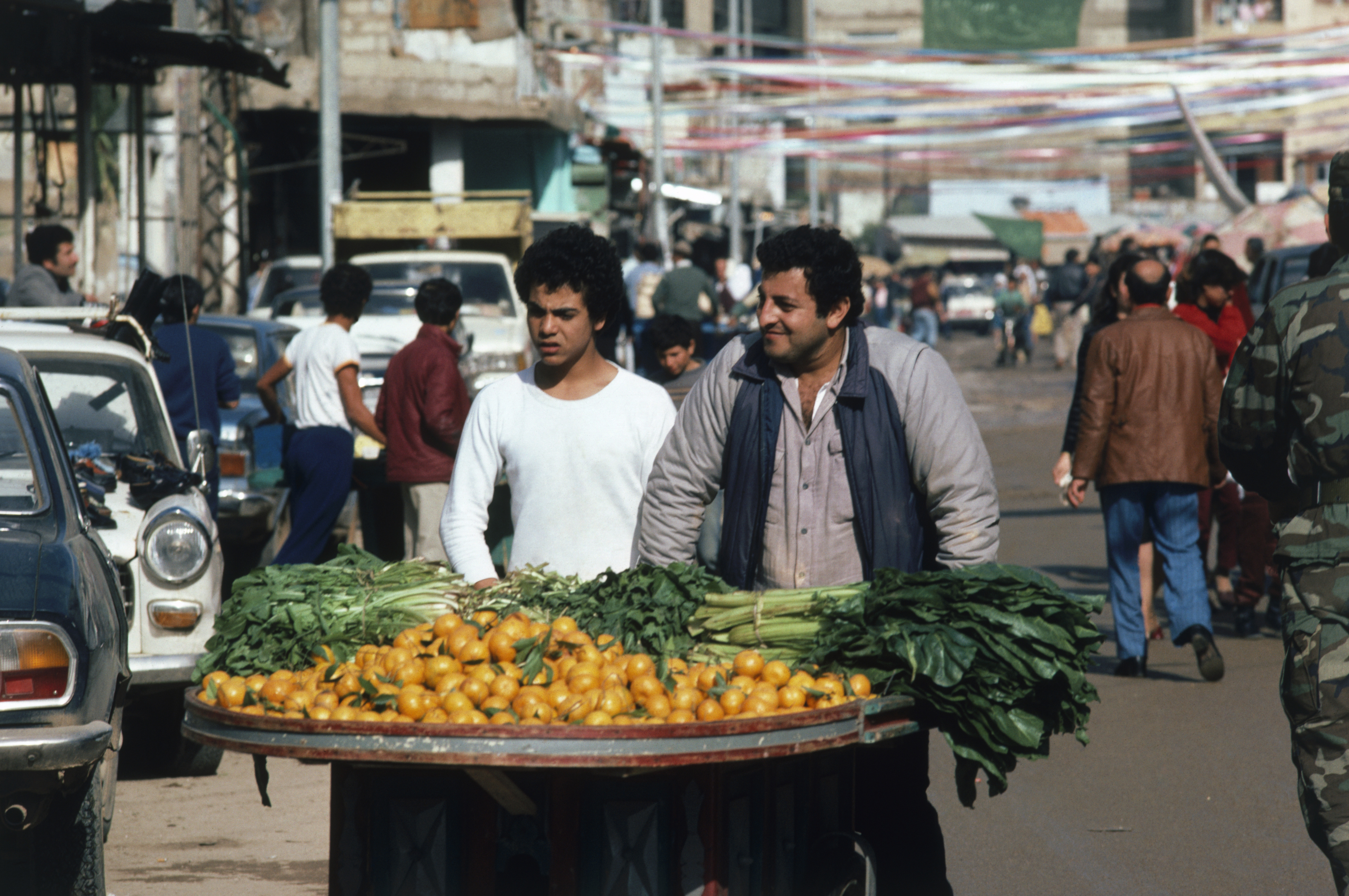 Two vendors selling oranges and vegetables from a cart walk through a war torn street in the Shatilla Palestinian refugee camp after heavy rains.. (Photo by Peter Charlesworth/LightRocket via Getty Images)