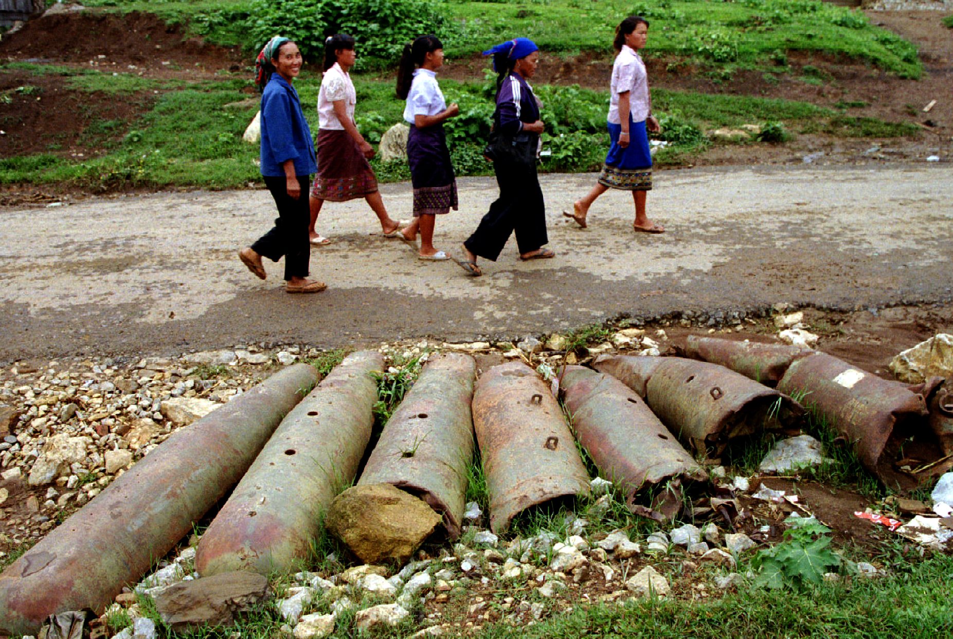 Laotian women walk past bombs and shells lie on the streets in this northern province. From 1964-1973, US planes dropped two million tonnes of bombs in Laos, many of them unexploded, still scattered throughout the countryside causing casualties to the Laotian people