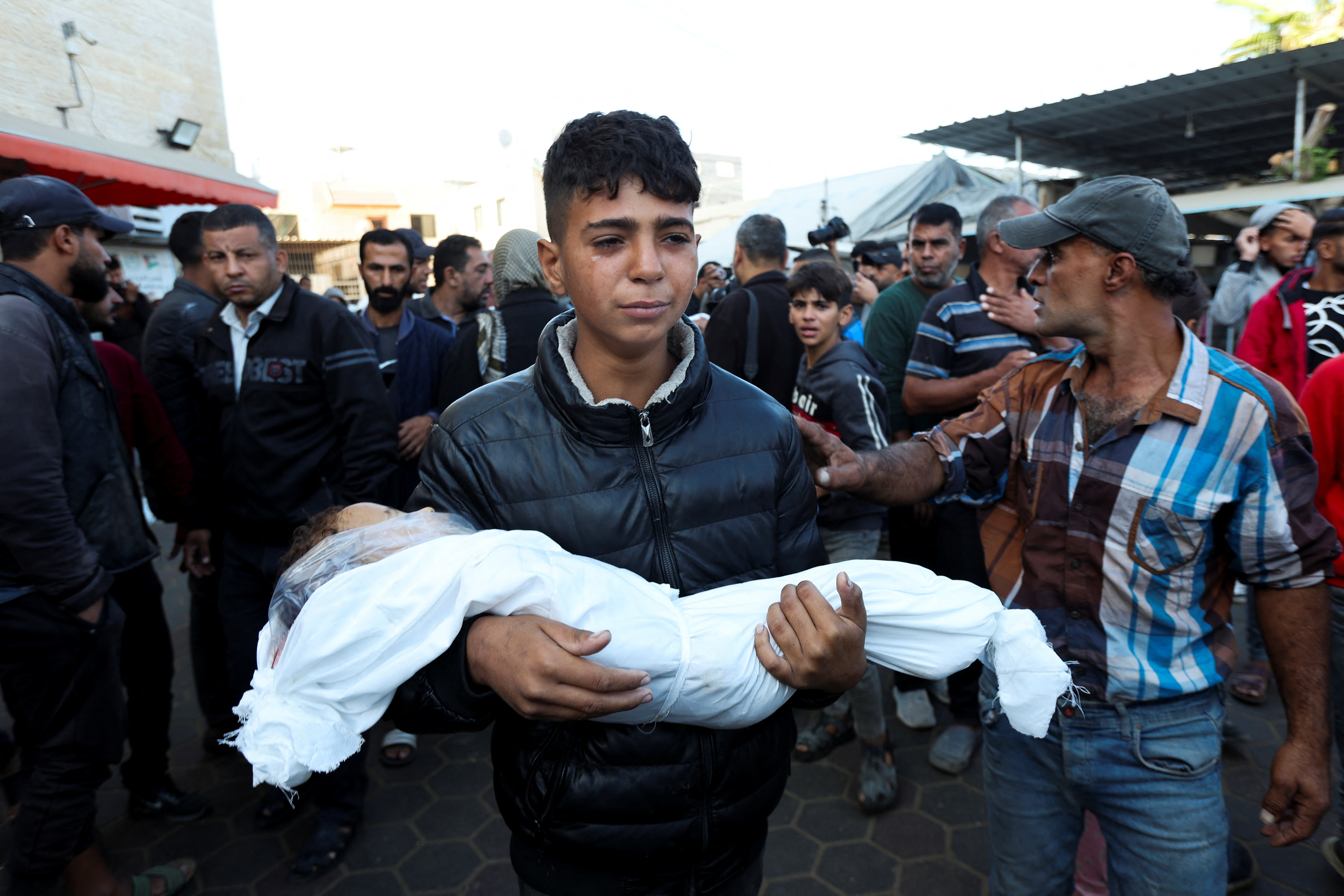SENSITIVE MATERIAL. THIS IMAGE MAY OFFEND OR DISTURB A Palestinian boy cries as he carries a body of a child who was killed in Israeli strikes, amid the Israel-Hamas conflict, at Al-Aqsa Martyrs Hospital in Deir Al-Balah, in the central Gaza Strip, October 29, 2024. REUTERS/Ramadan Abed TPX IMAGES OF THE DAY