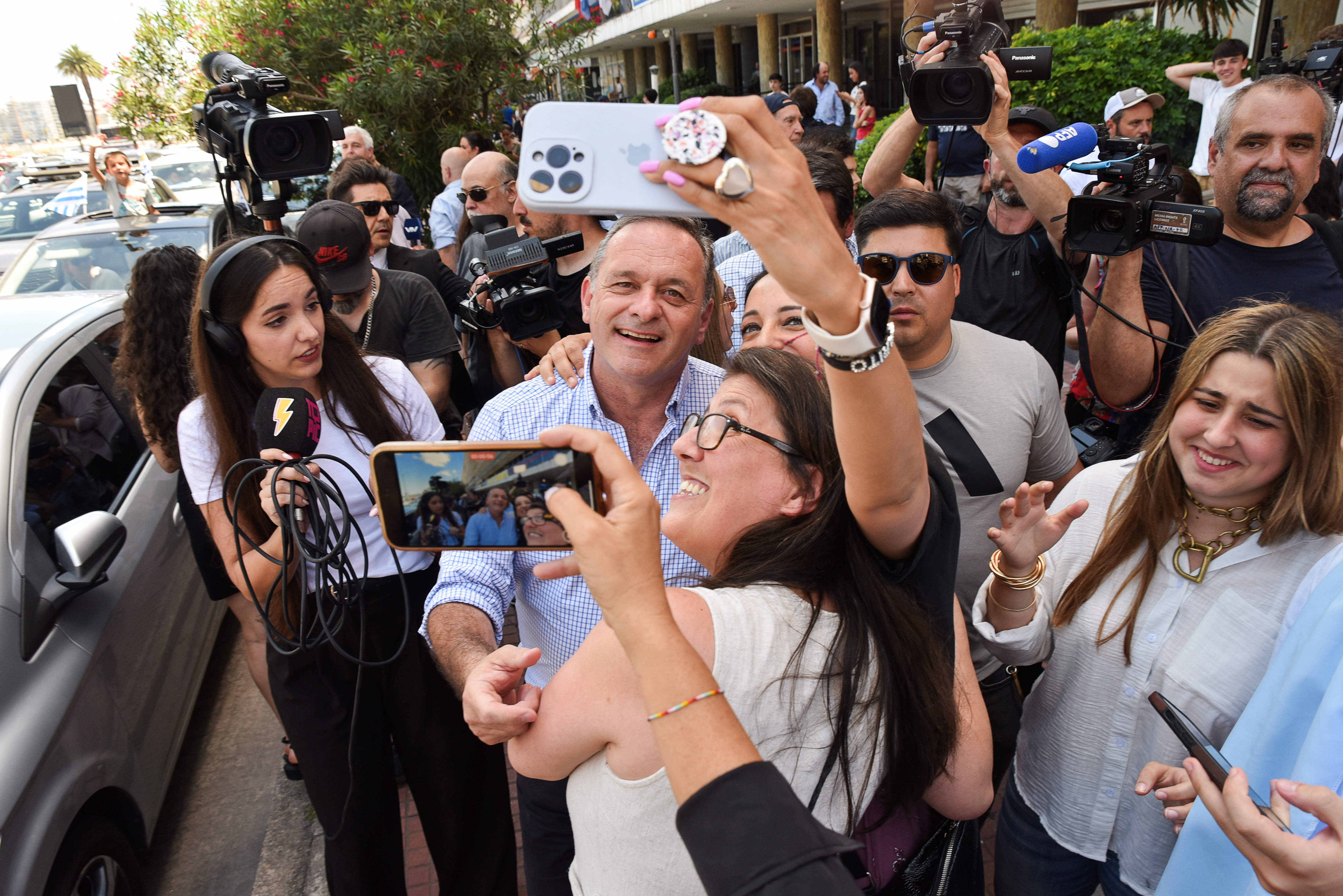 Alvaro Delgado poses for selfies outside a polling station.