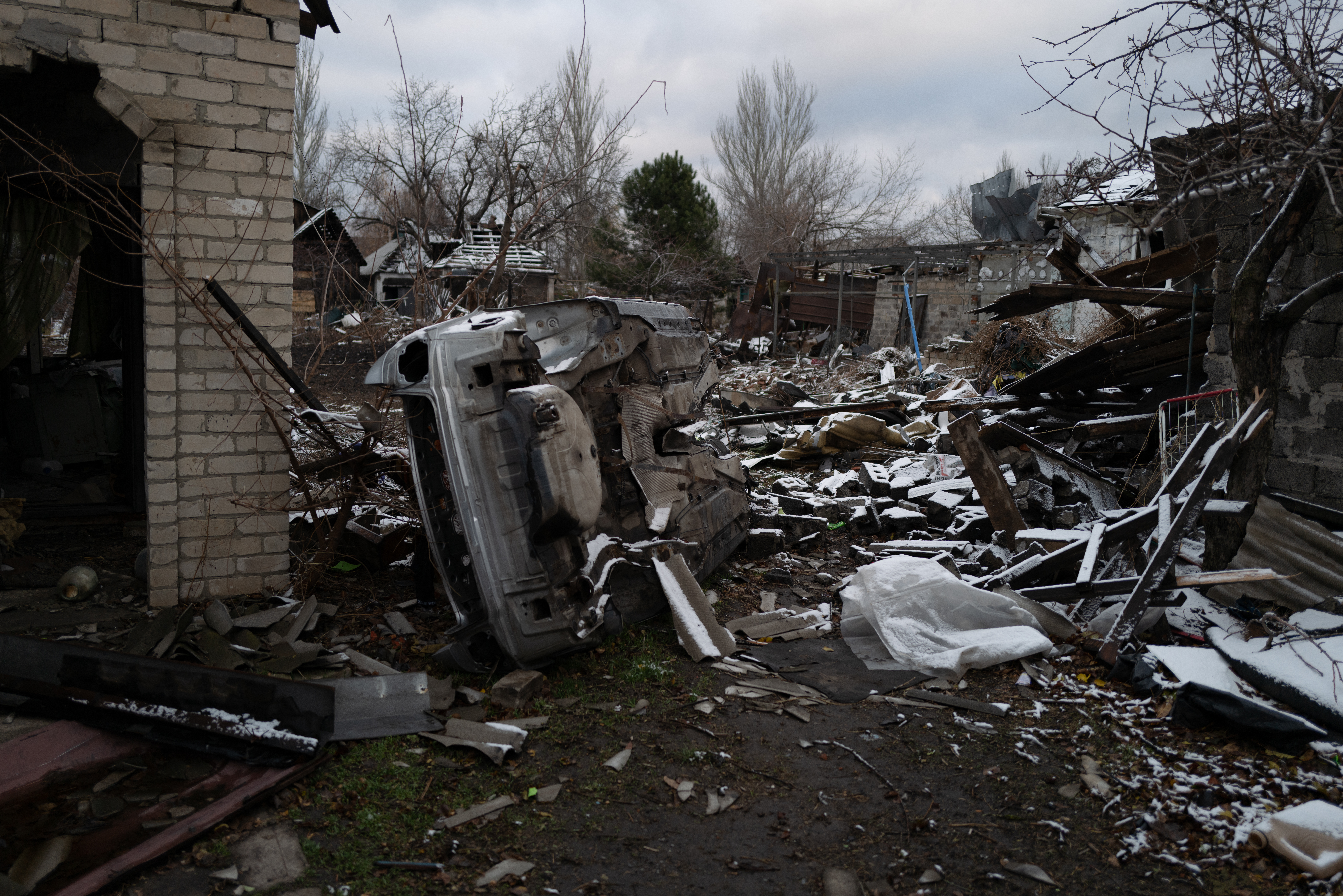 This photograph shows a destroyed car and rubble from a recent shelling in Pokrovsk, Donetsk region, on November 24, 2024. The first snow falls on Ukraine and settlements close to the front line, while Russia continues to shell energy infrastructures, promising a "very difficult winter" according to Kiev. (Photo by Florent VERGNES / AFP)