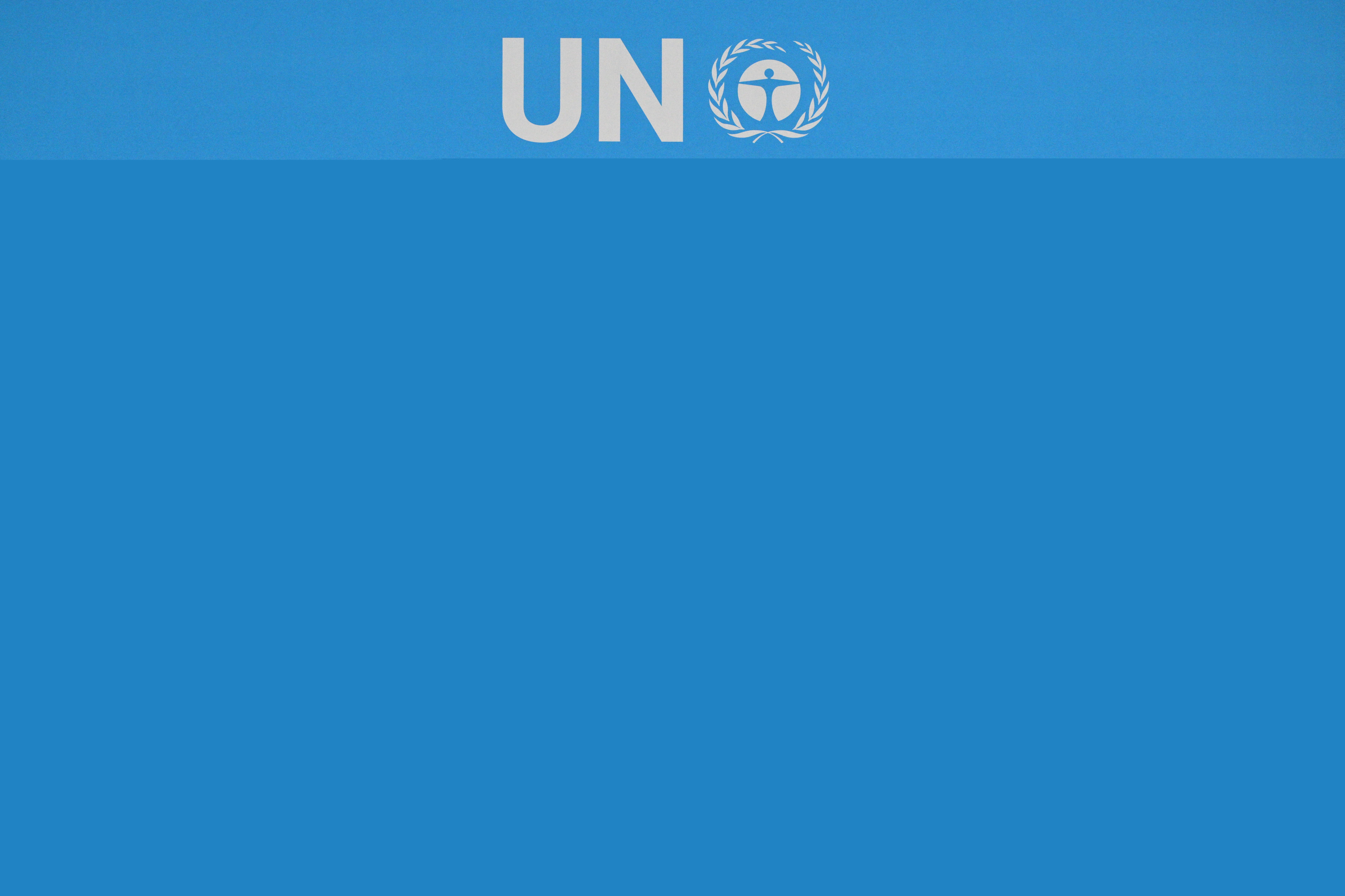 people stand in front of a light blue sign at a conference