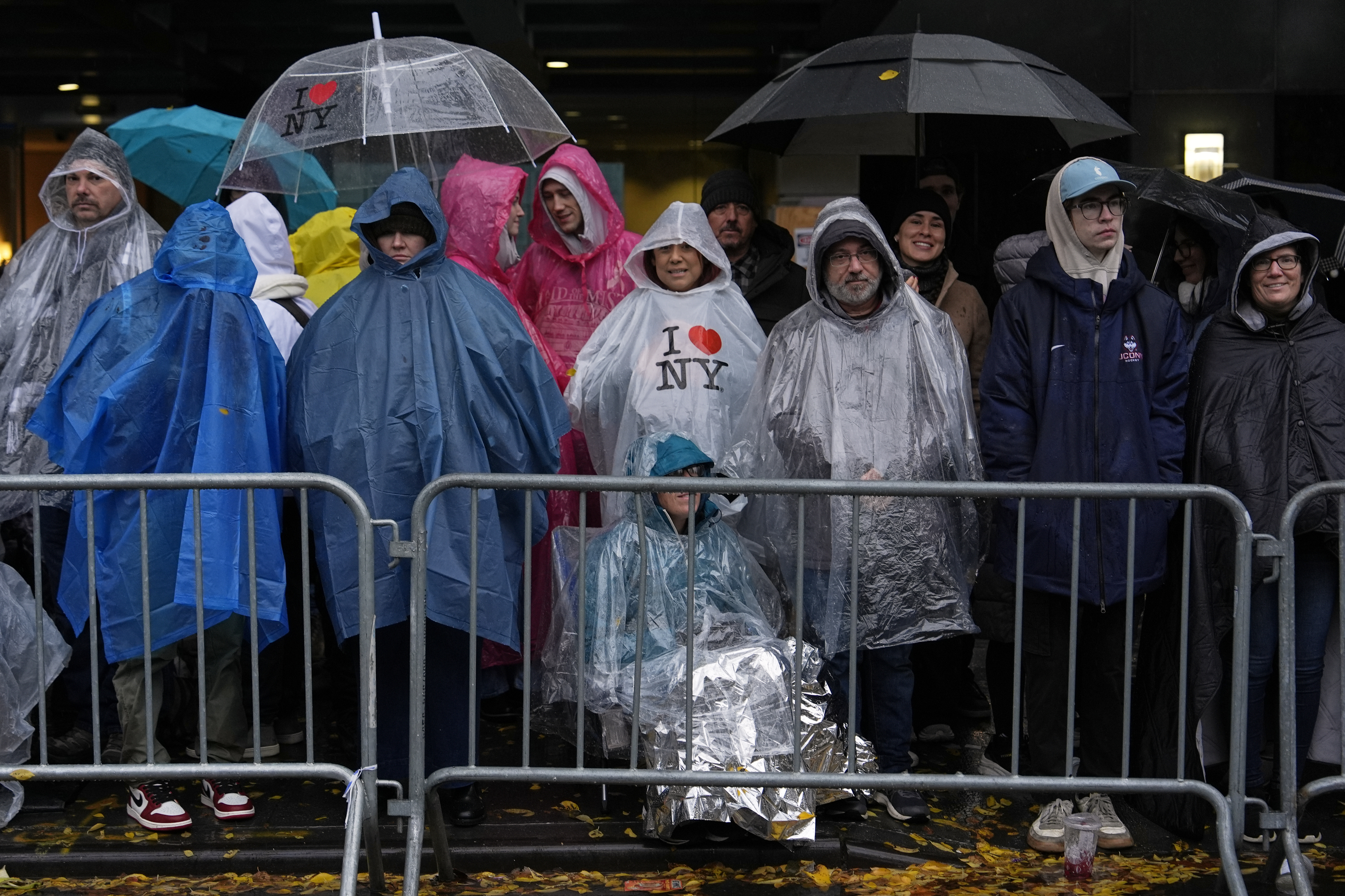 Onlookers watch the Macy's Thanksgiving Parade in raincoats and with umbrellas to shield from the rain