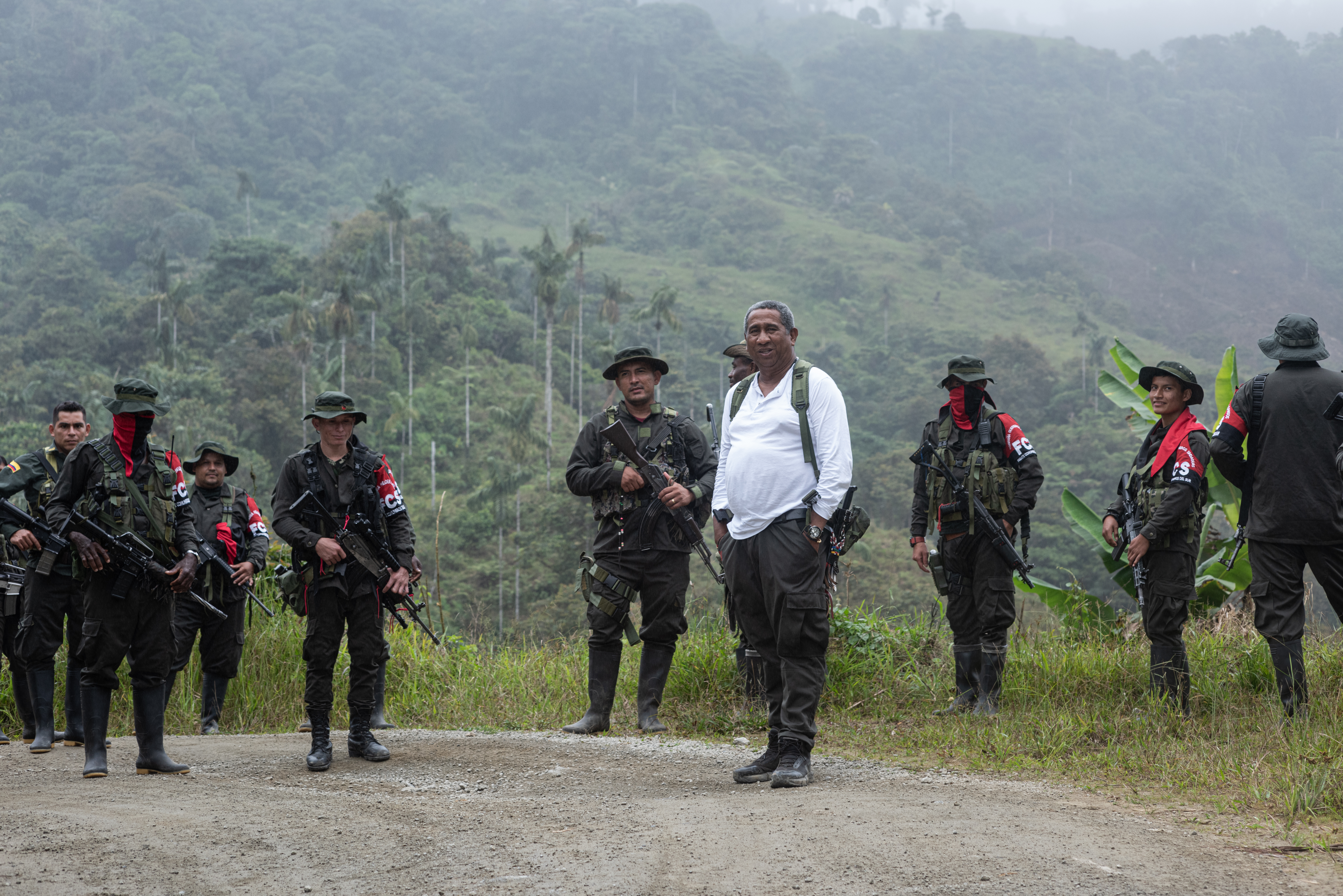 Armed Comuneros del Sur fighters stand behind a man in a white shirt, identified as their commander.