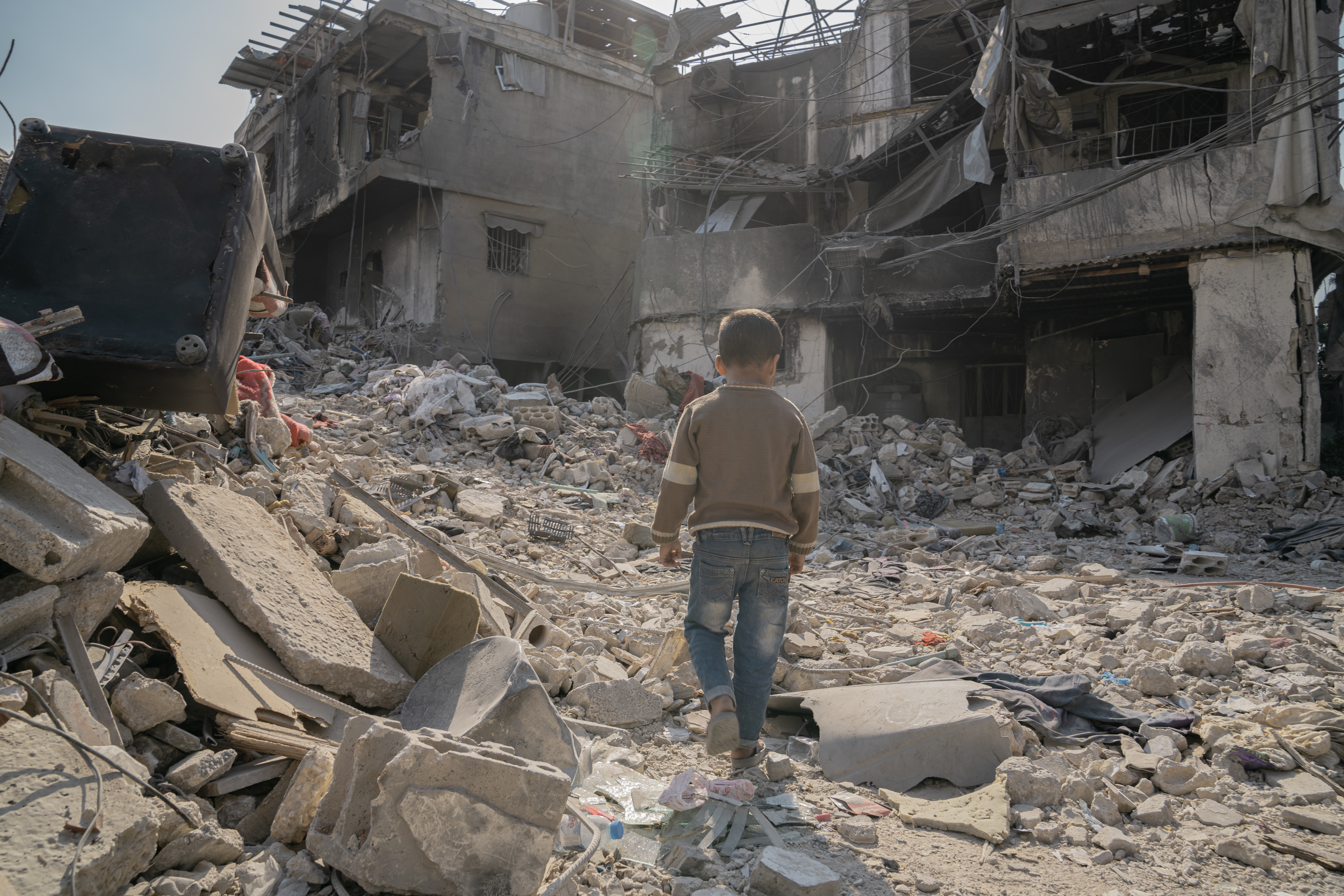 A Lebanese child searches through the rubble of his uncle's house that has been bombed in an Israeli air attack