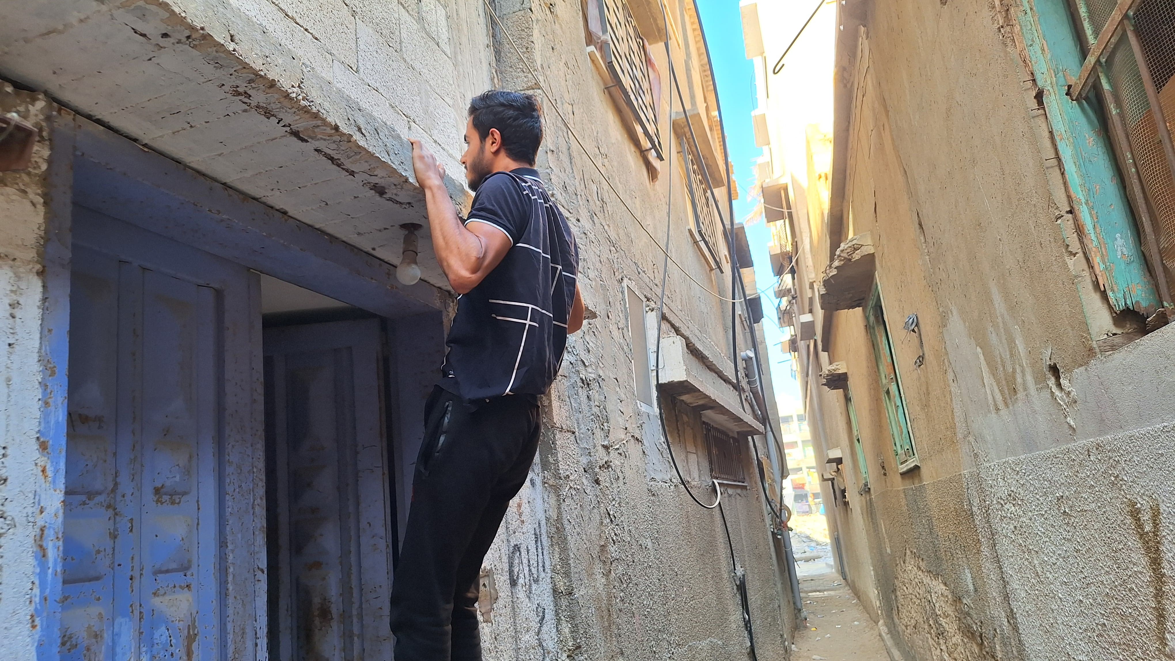 Mohamed Hatem performing muscle-ups outside a residential building in Gaza.