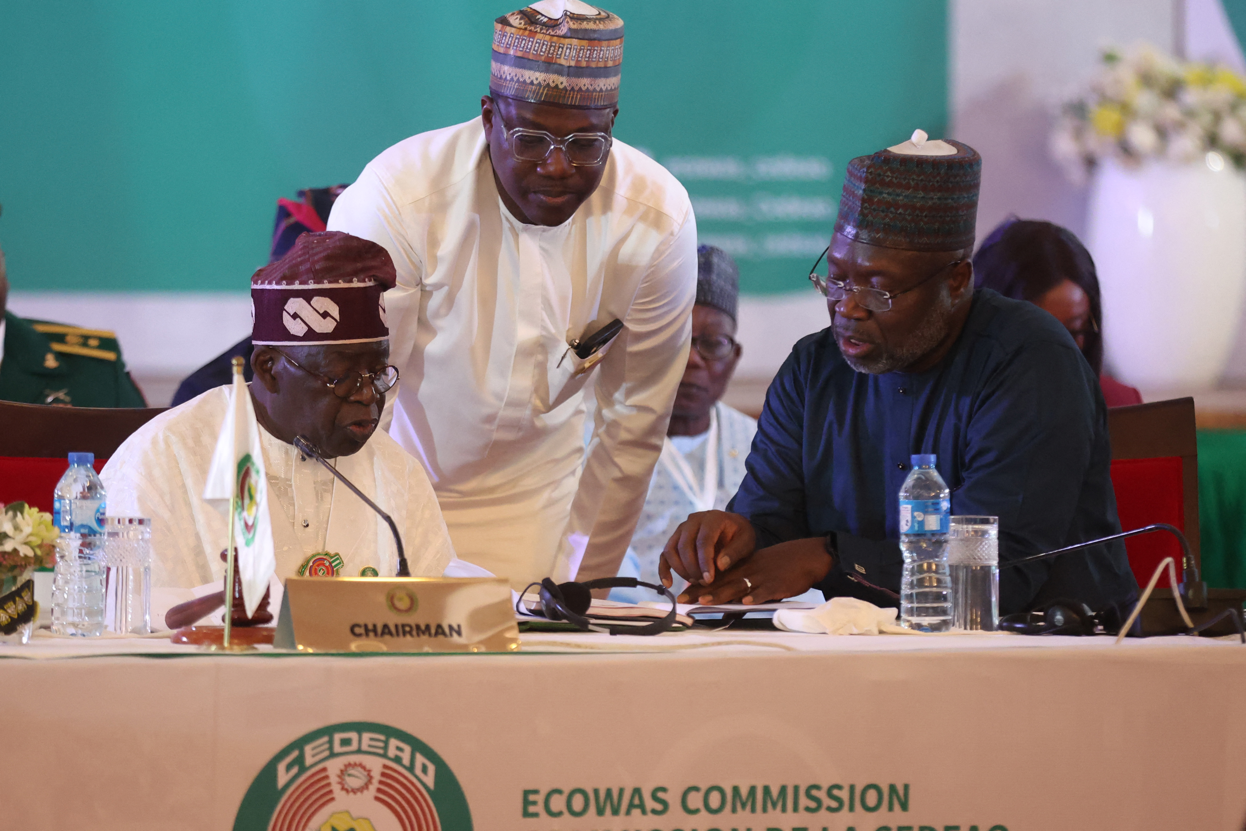 Nigeria President and Chairman of the Economic Community of West African States (ECOWAS) Bola Ahmed Tinubu (L), Principal Private Secretary to President Tinubu Hakeem Muri-Okunola (C) and President of ECOWAS Omar Touray discuss during the opening session of ECOWAS 66th Ordinary Session of the Authority of Heads of States and Government in Abuja on December 15, 2024 - West African leaders from the regional group ECOWAS met on December 15, 2024 for a summit with three nation members led by military governments on the brink of quitting the bloc. Before the Economic Community of West African States meeting, Burkina Faso, Mali and Niger reaffirmed as "irreversible" their decision a year ago to quit the group, which they condemned as subservient to ex-colonial ruler France (Photo by Kola Sulaimon / AFP)