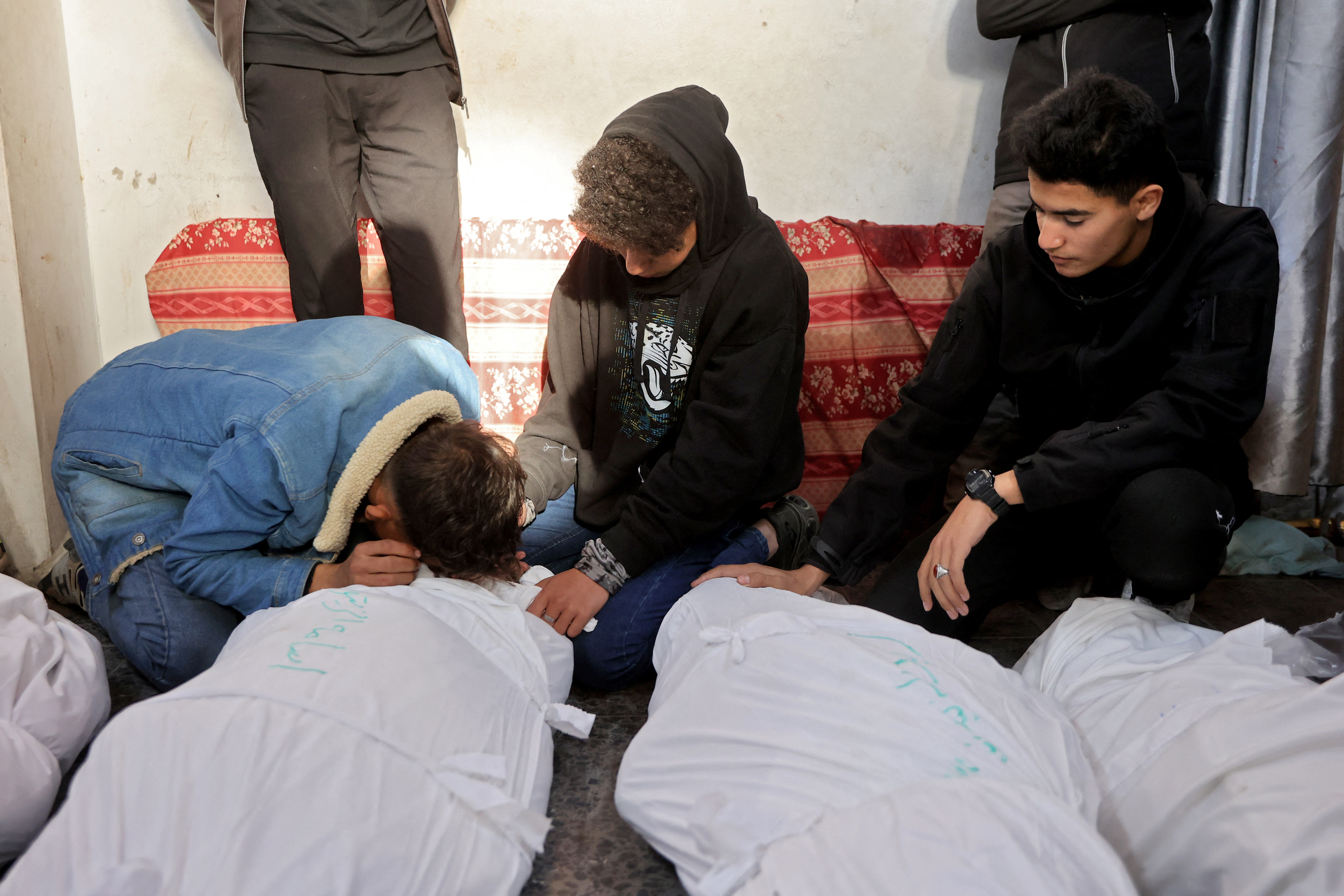 People mourn over the body of loveds ones killed during an Israeli strike, at Al-Ahli Arab hospital, also known as the Baptist hospital, in Gaza City on December 19