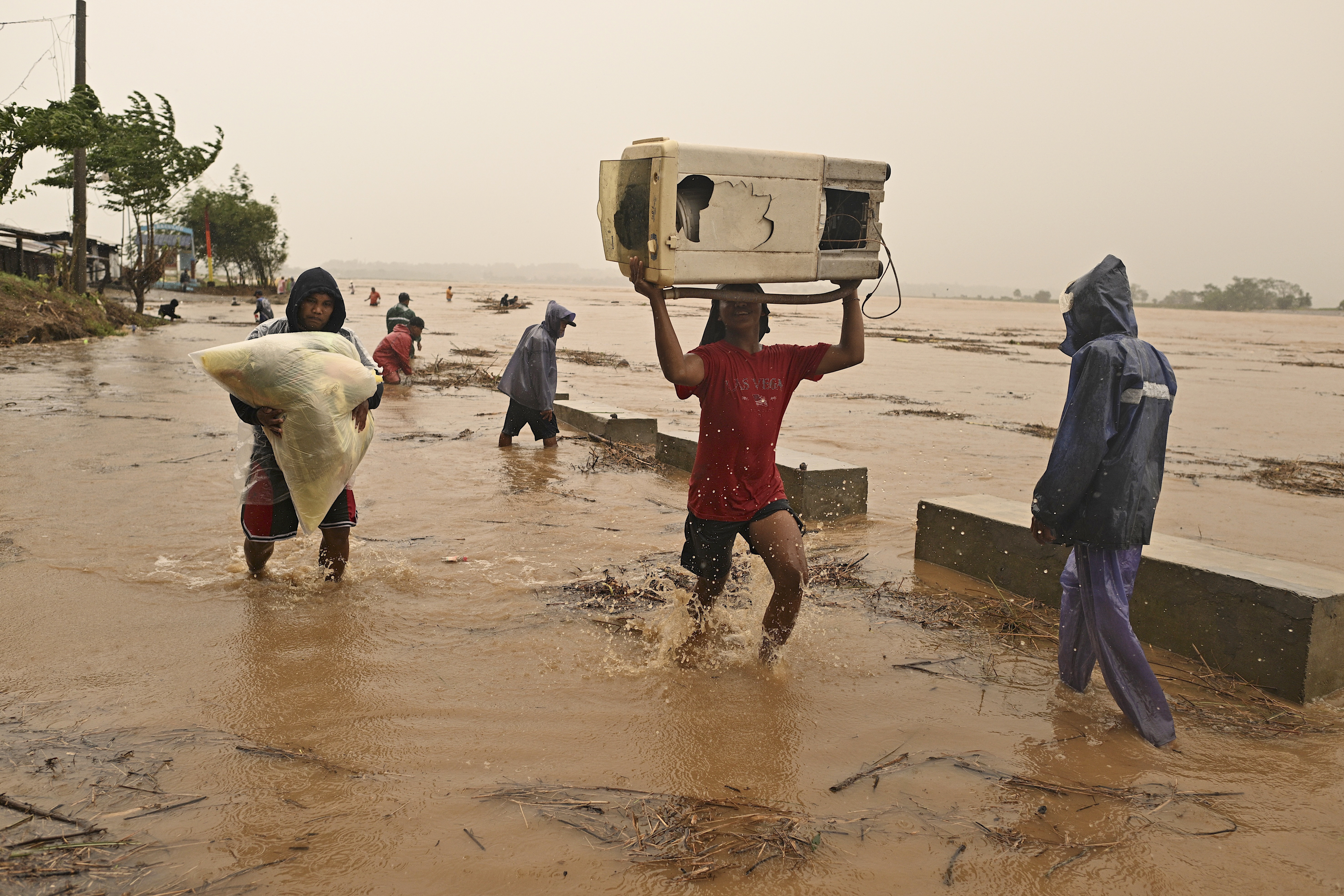 Residents carry their belongings as the river swells, following heavy rains from Typhoon Toraji in Ilagan City, Isabela province, northern Philippines on Monday, Nov. 11, 2024