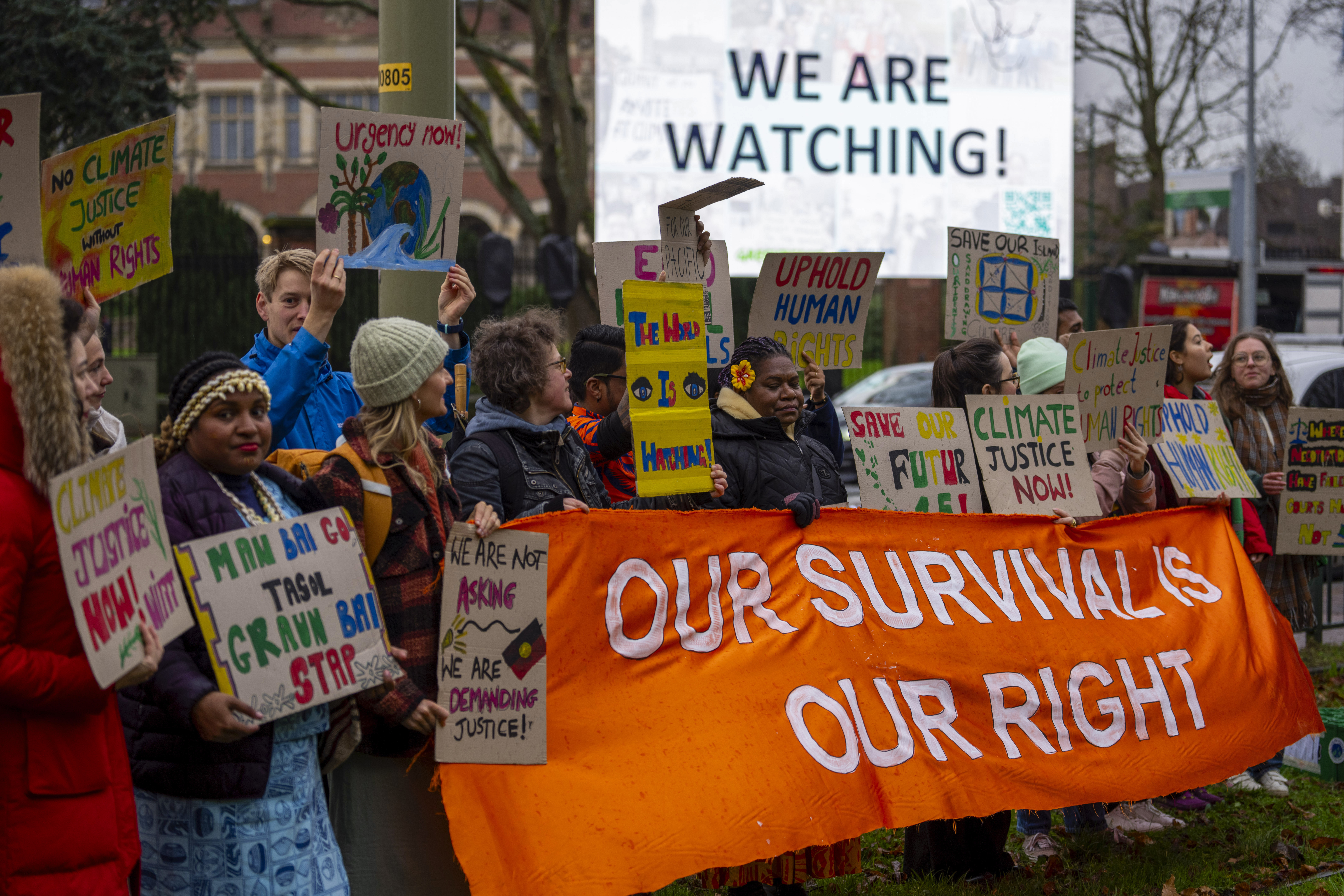people hold an orange banner that says our survival our rights at a protest