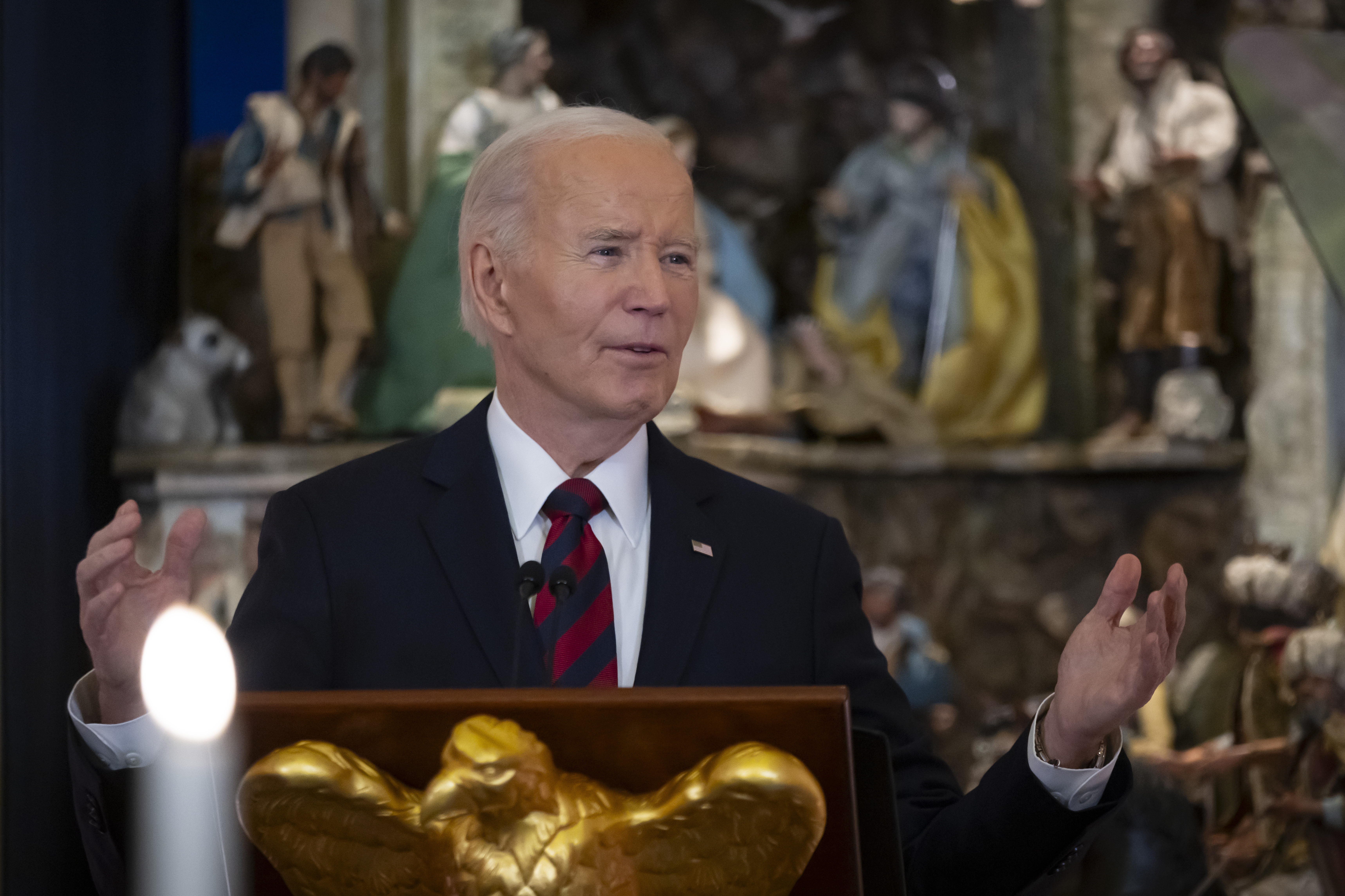 President Joe Biden gives a speech behind a podium with a golden eagle at its base