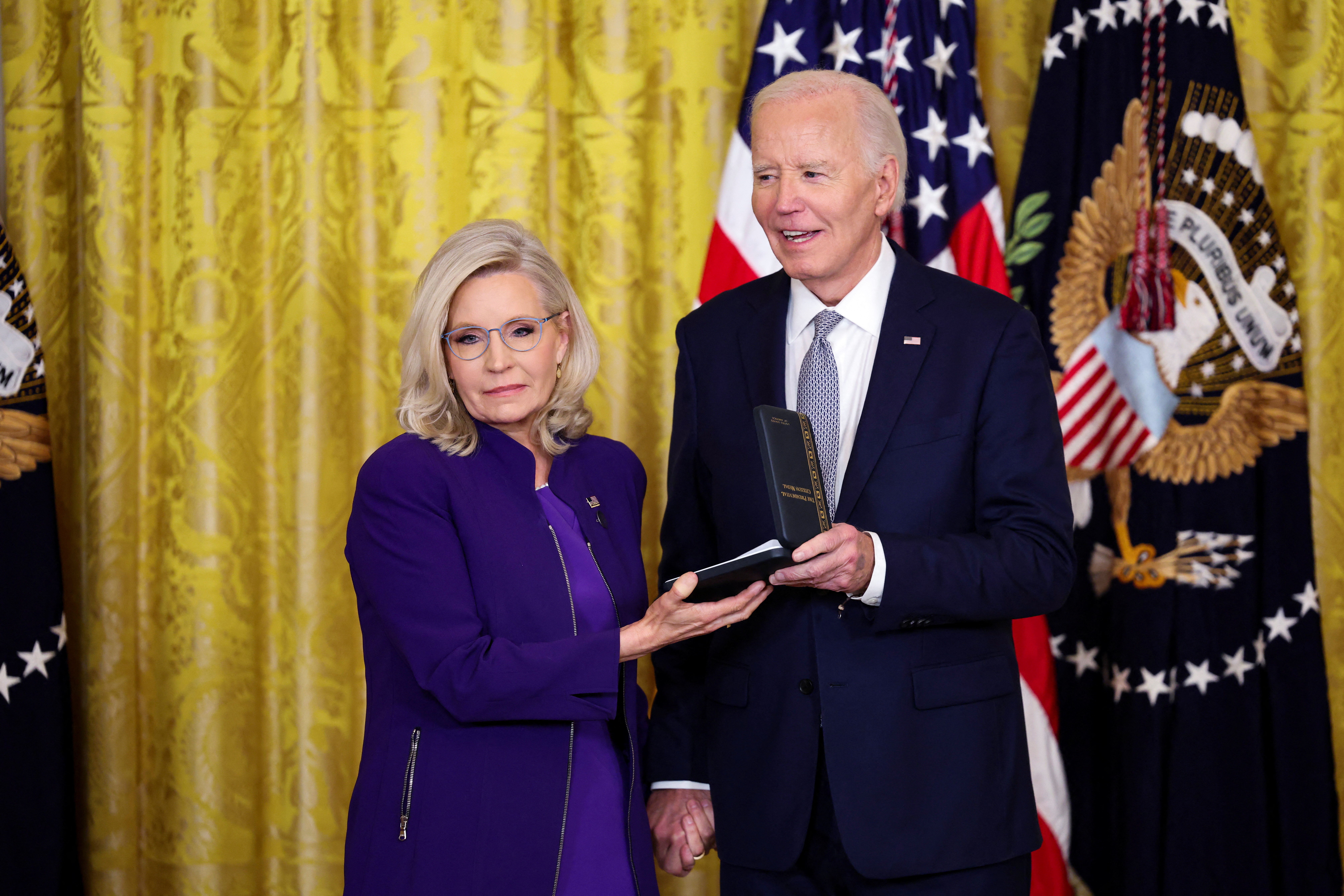 Joe Biden hands a medal to Liz Cheney at the White House