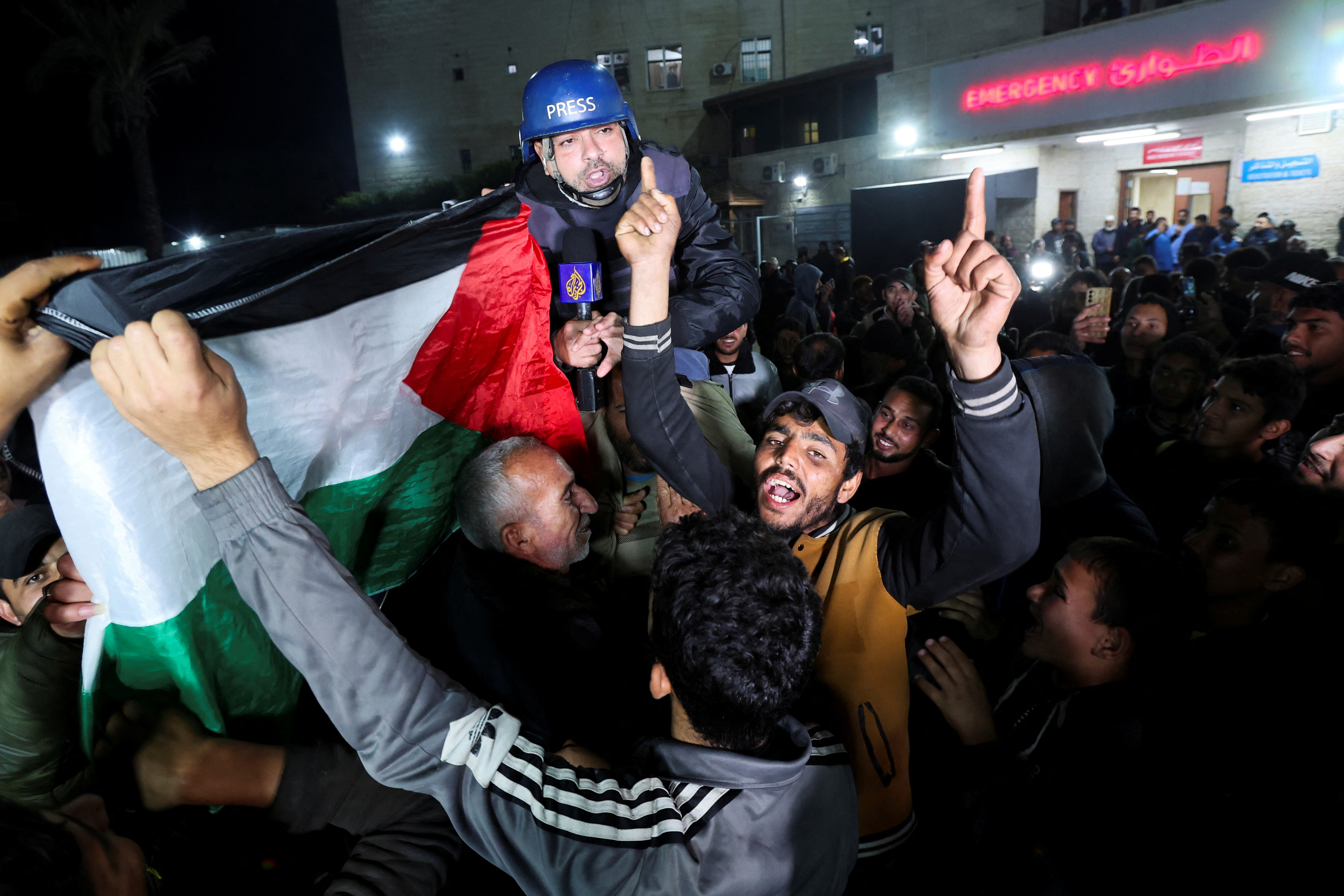 Palestinians celebrating news on a ceasefire with Israel, carry Al Jazeera correspondent Ashraf Amrah as he reports live in Deir Al-Balah in the central Gaza Strip, January 15, 2025 [Ramadan Abed/Reuters]