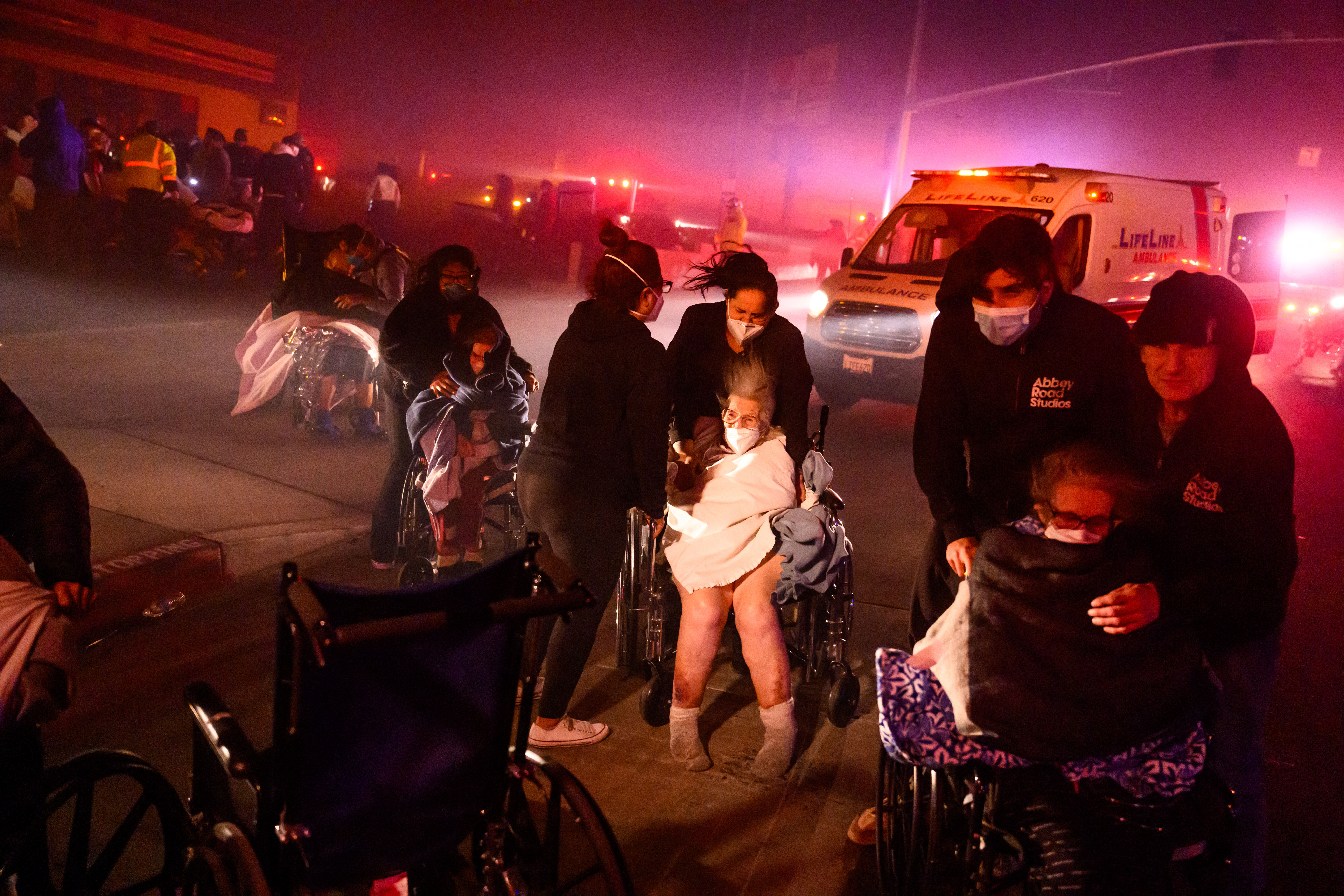 Elderly patients are quickly evacuated into emergency vehicles as embers and flames approach during the Eaton fire in Pasadena, California on January 7, 2025. A ferocious wildfire in a Los Angeles suburb devoured buildings and sparked panicked evacuations January 7, as hurricane-force winds tore through the region. More than 200 acres (80 hectares) was burning in Pacific Palisades, a upscale spot with multi-million dollar homes in the Santa Monica Mountains. Across town, on the northern edge of Los Angeles, another fire broke out in Eaton Canyon, near Pasadena, quickly consuming 200 acres (81 hectares) later in the night, according to Angeles National Forest officials. (Photo by JOSH EDELSON / AFP)