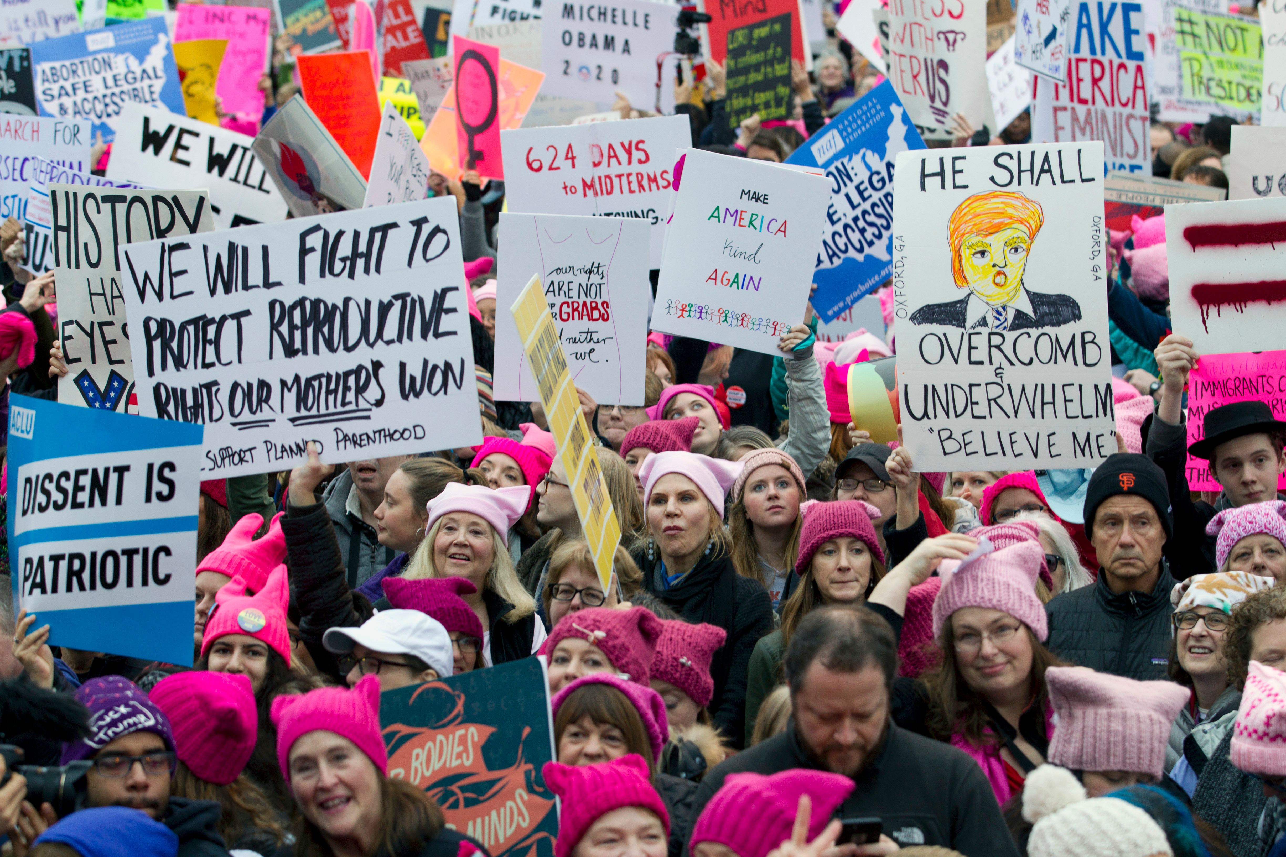 Women's March protesters hold up handwritten signs.