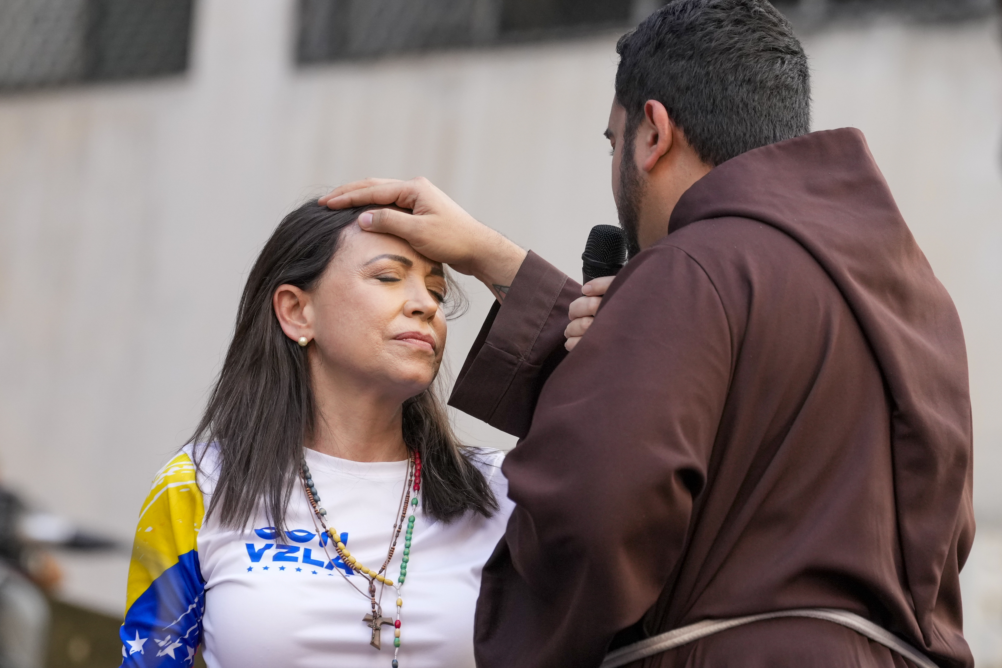 A priest blesses Maria Corina Machado
