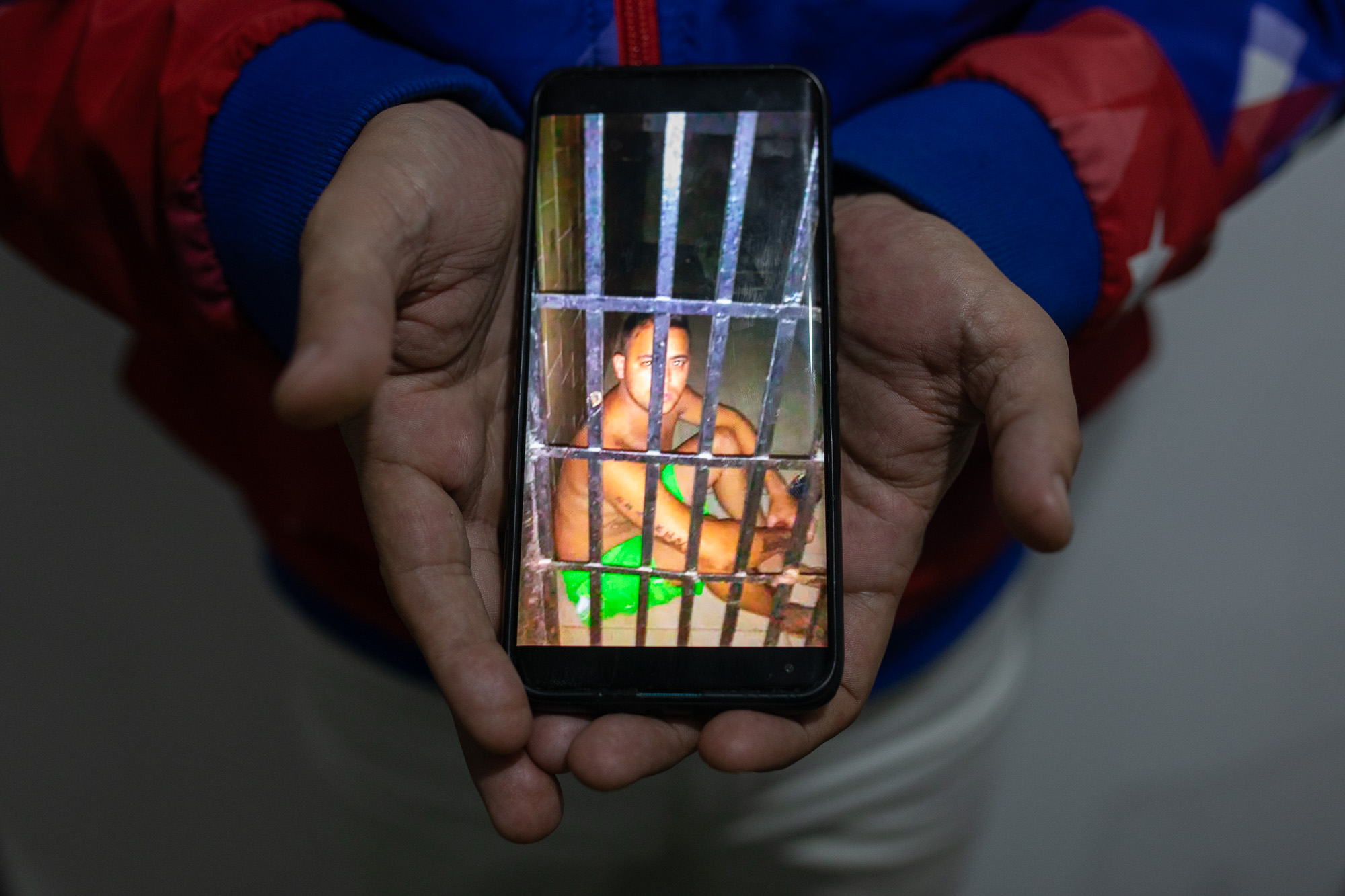 Jesus Medina holds up a phone featuring an emaciated photo of himself in prison