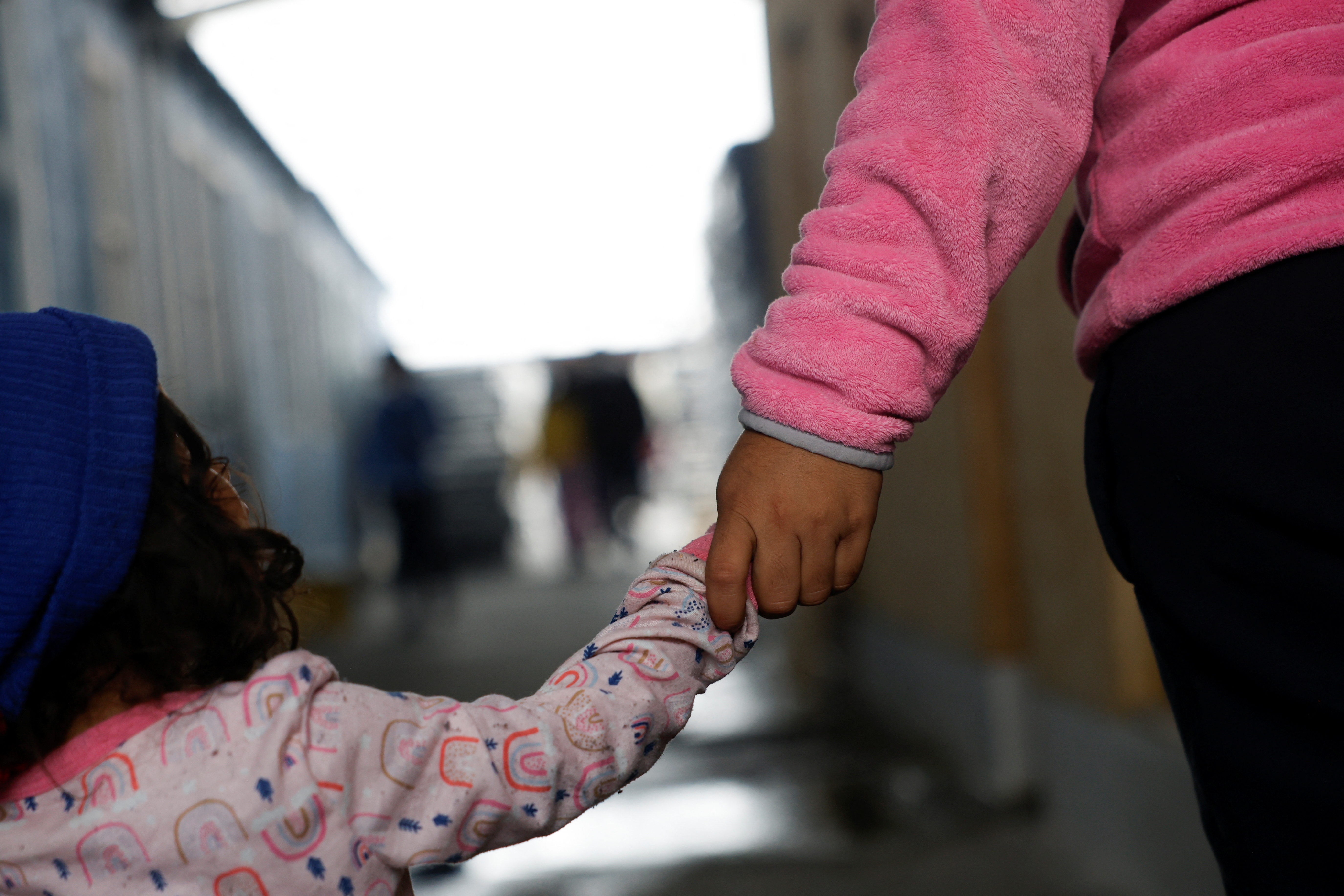 A young child holds hands with their parent in Reynosa, Mexico