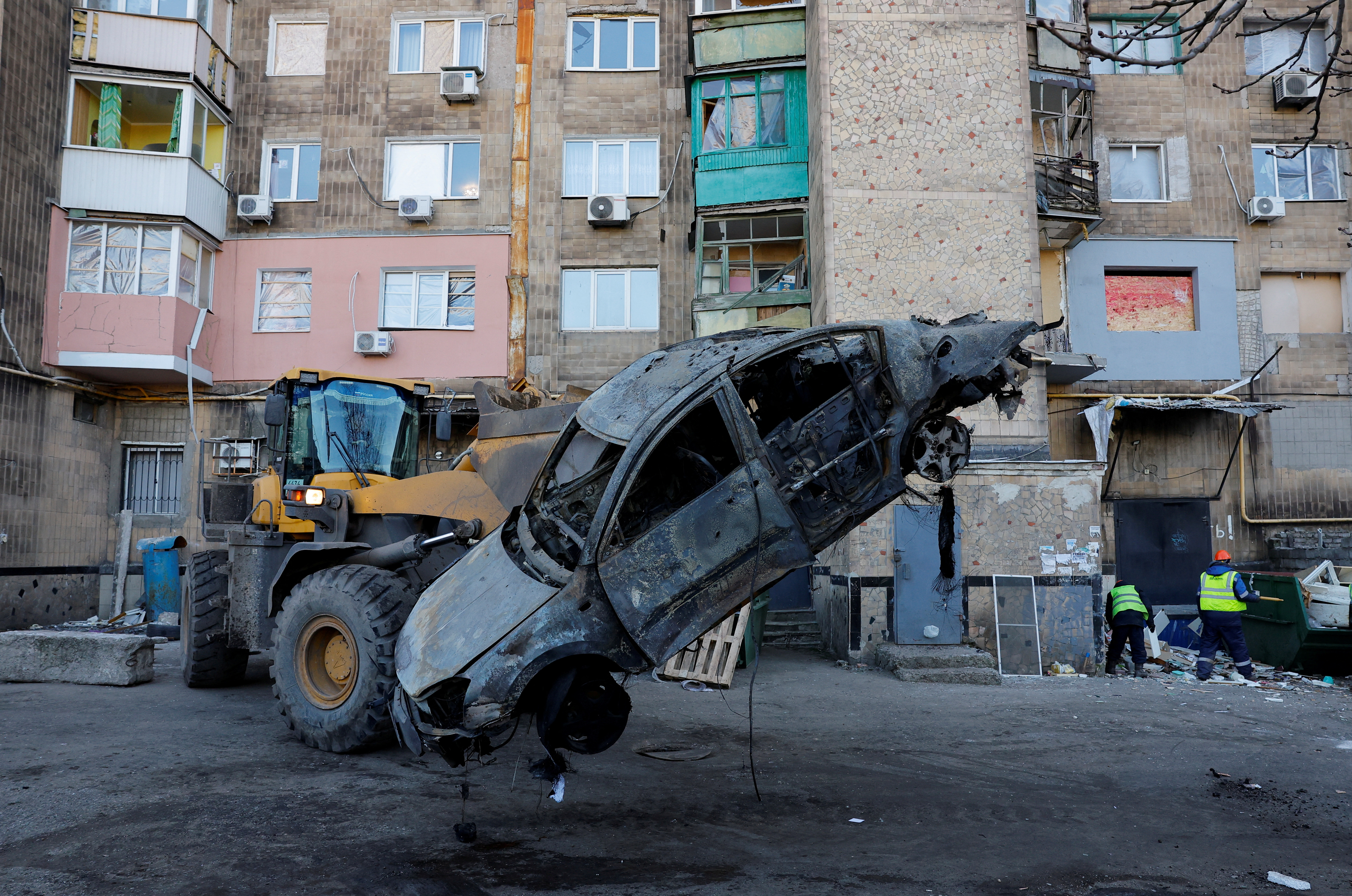 Specialists remove a burnt car in the courtyard of a damaged multi-storey residential building following recent shelling, which local Russian-installed authorities called a Ukrainian military strike, in the course of Russia-Ukraine conflict in Makiivka (Makeyevka), a Russian controlled region of Ukraine, February 9, 2025. REUTERS/Alexander Ermochenko