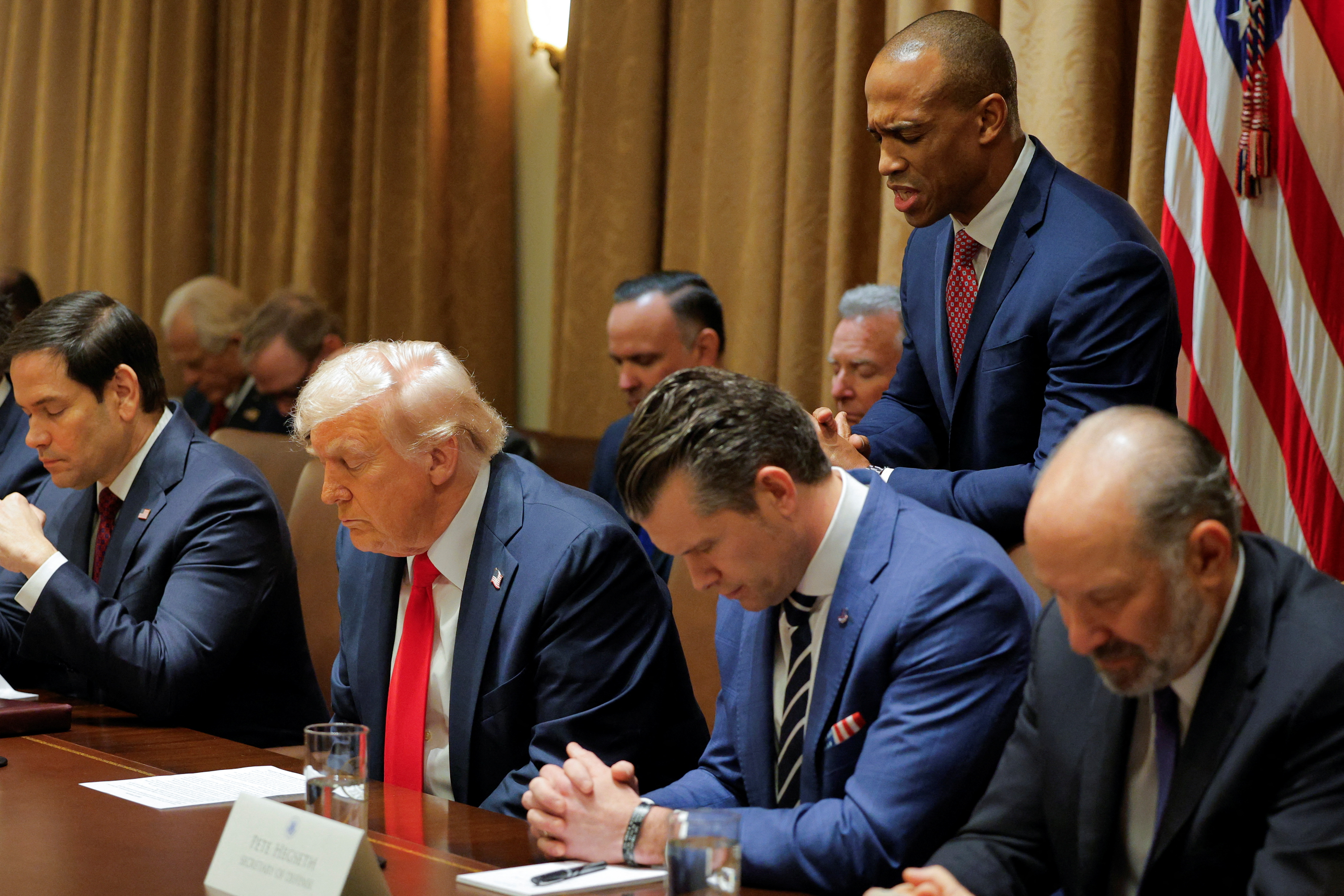 Donald Trump and Pete Hegseth listen as the Housing and Urban Development chief Scott Turner leads a prayer.