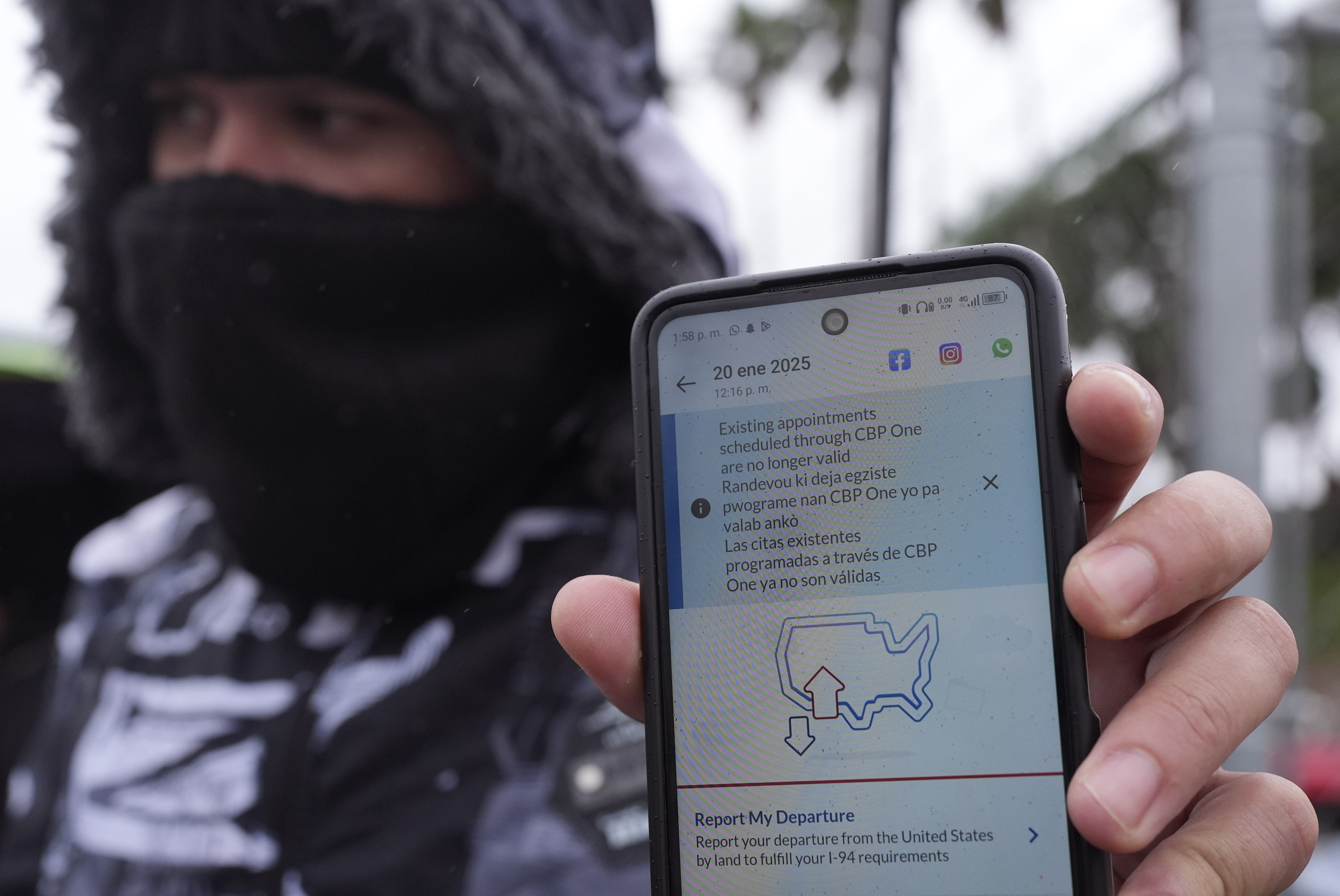 A migrant holds up a phone screen that shows CBP One is no longer available.