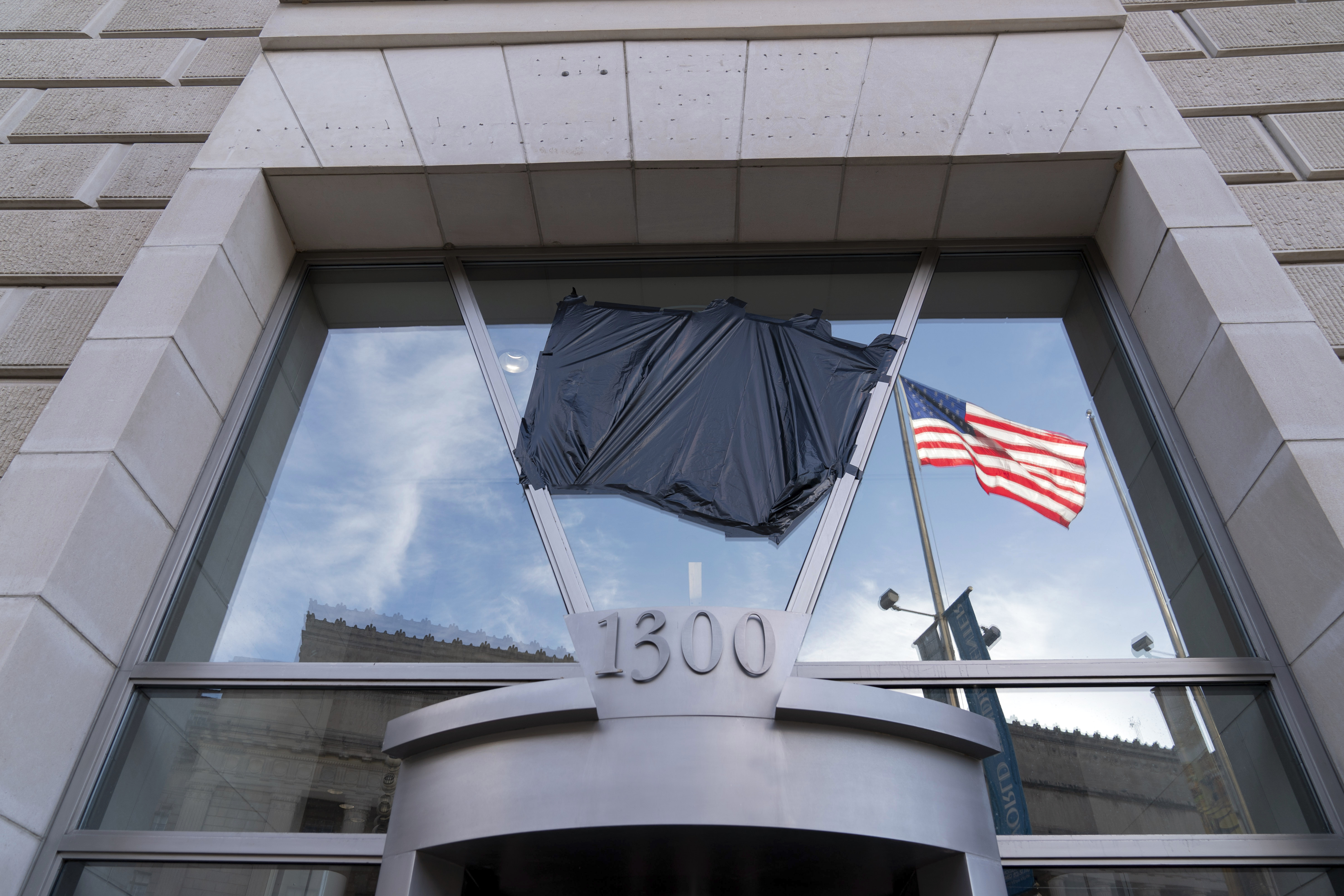 Black plastic tarp covers the logo for USAID on an outside office door.