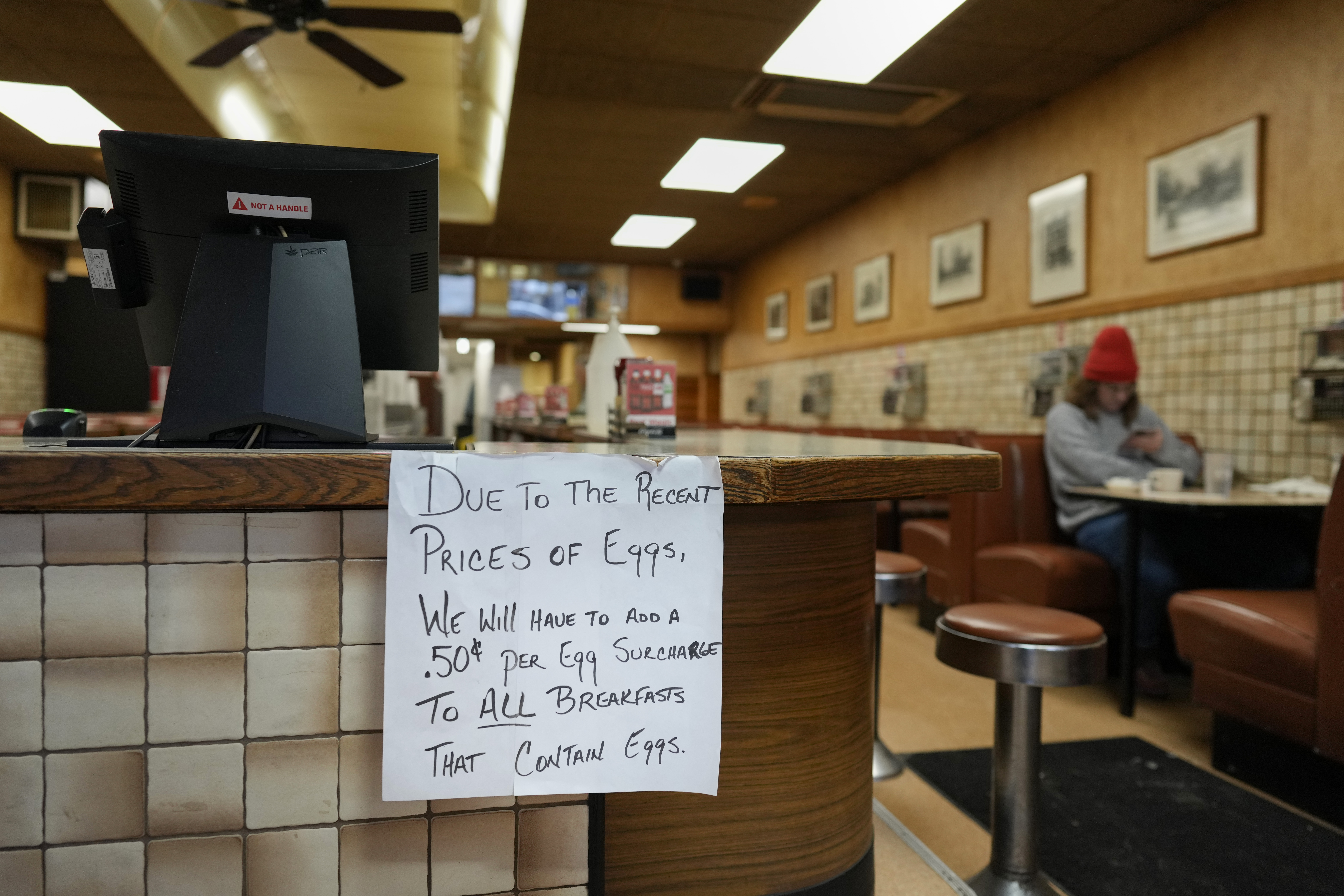 A sign is posted at the register read "Due to the recent price of eggs, we will have to add a .50 cent per egg surcharge to all breakfasts that contain eggs." at the Pepper Pod Restaurant, Thursday, Feb.13, 2025, Newport, Ky. (AP Photo/Carolyn Kaster)