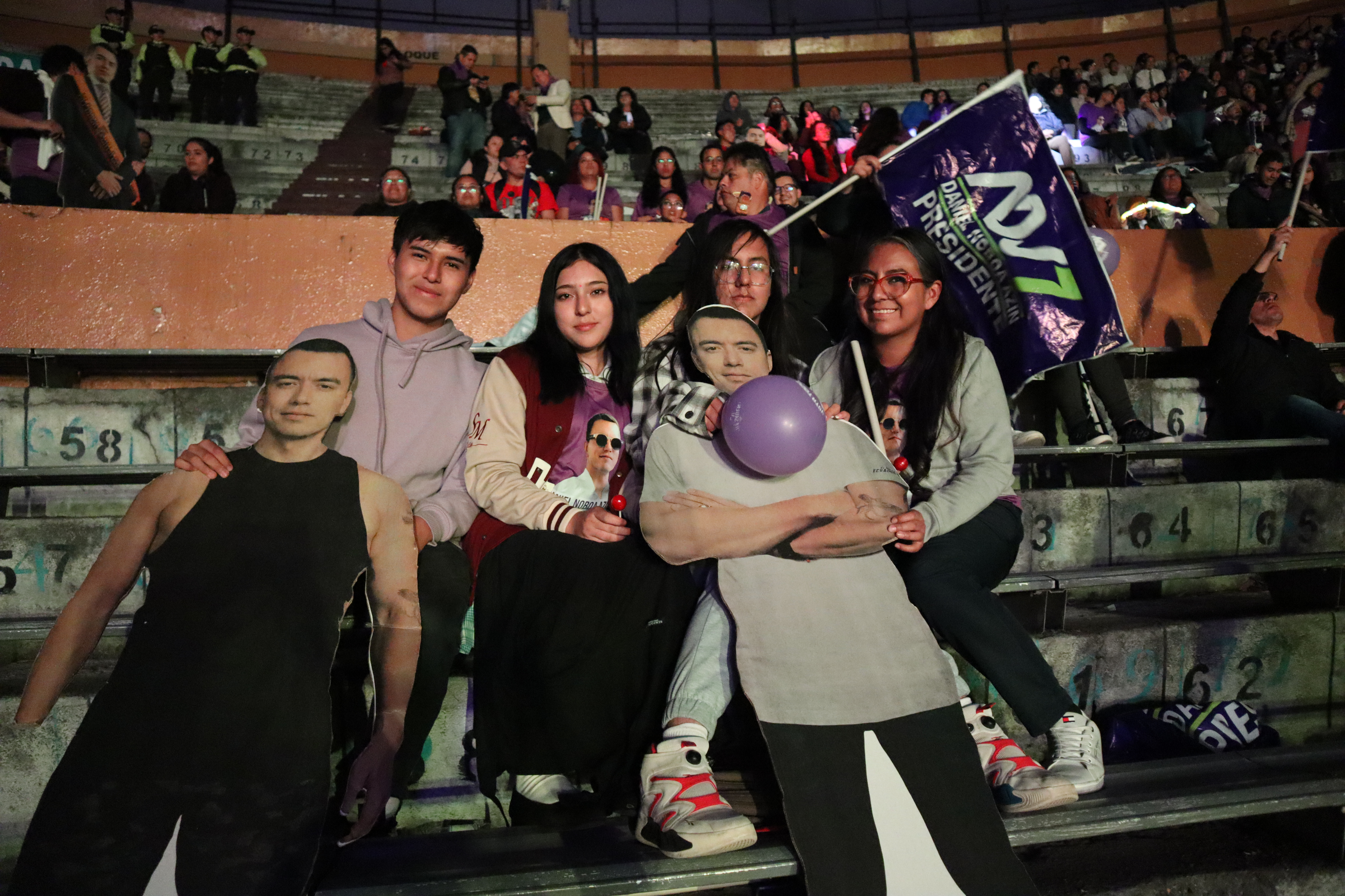 Leslie Grijalva, 30, and her teenage friends (aged 17) pose in front of a cardboard cut-out of Noboa at his closing campaign event.