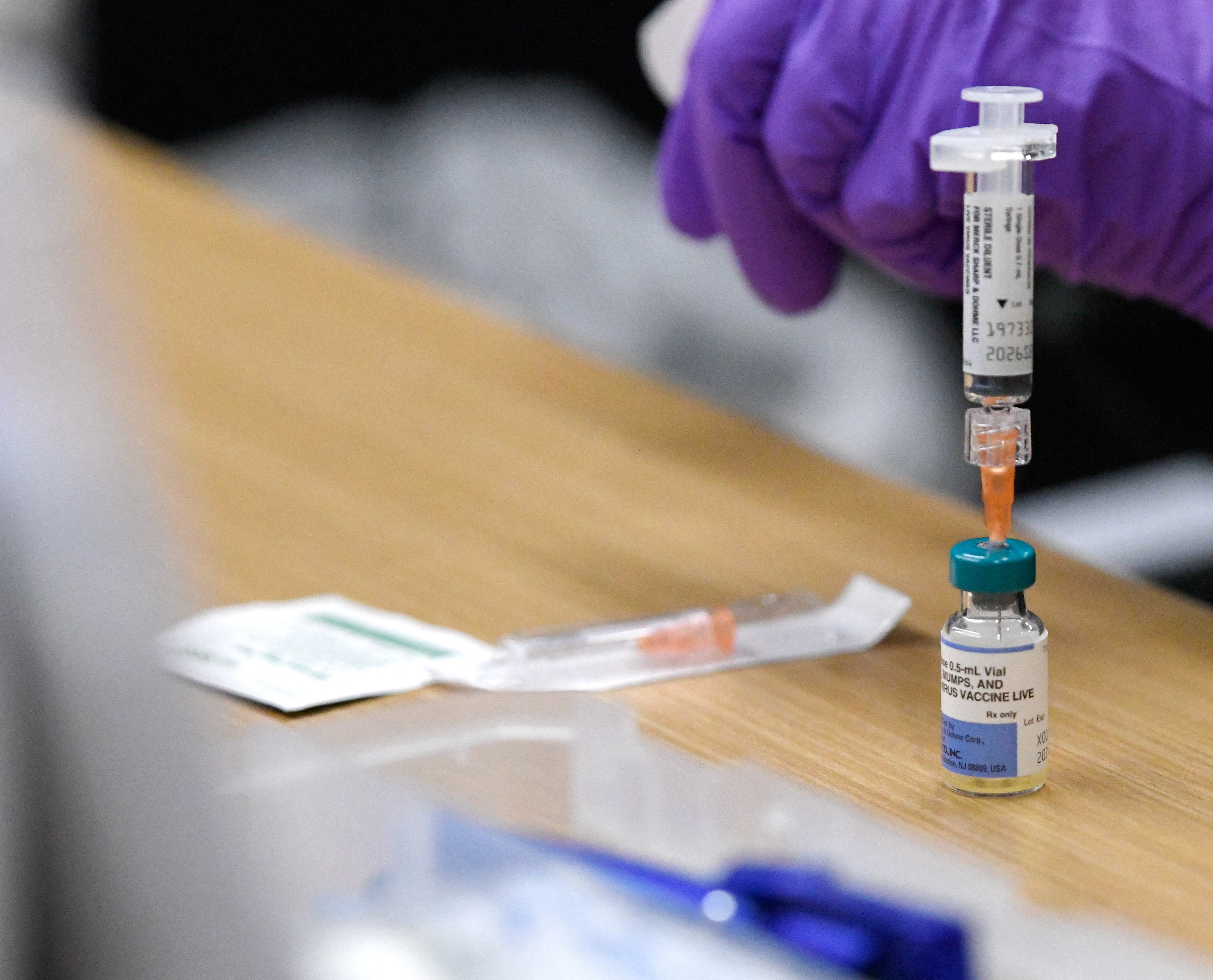 A syringe extracts vaccine from a vial at a healthcare center.