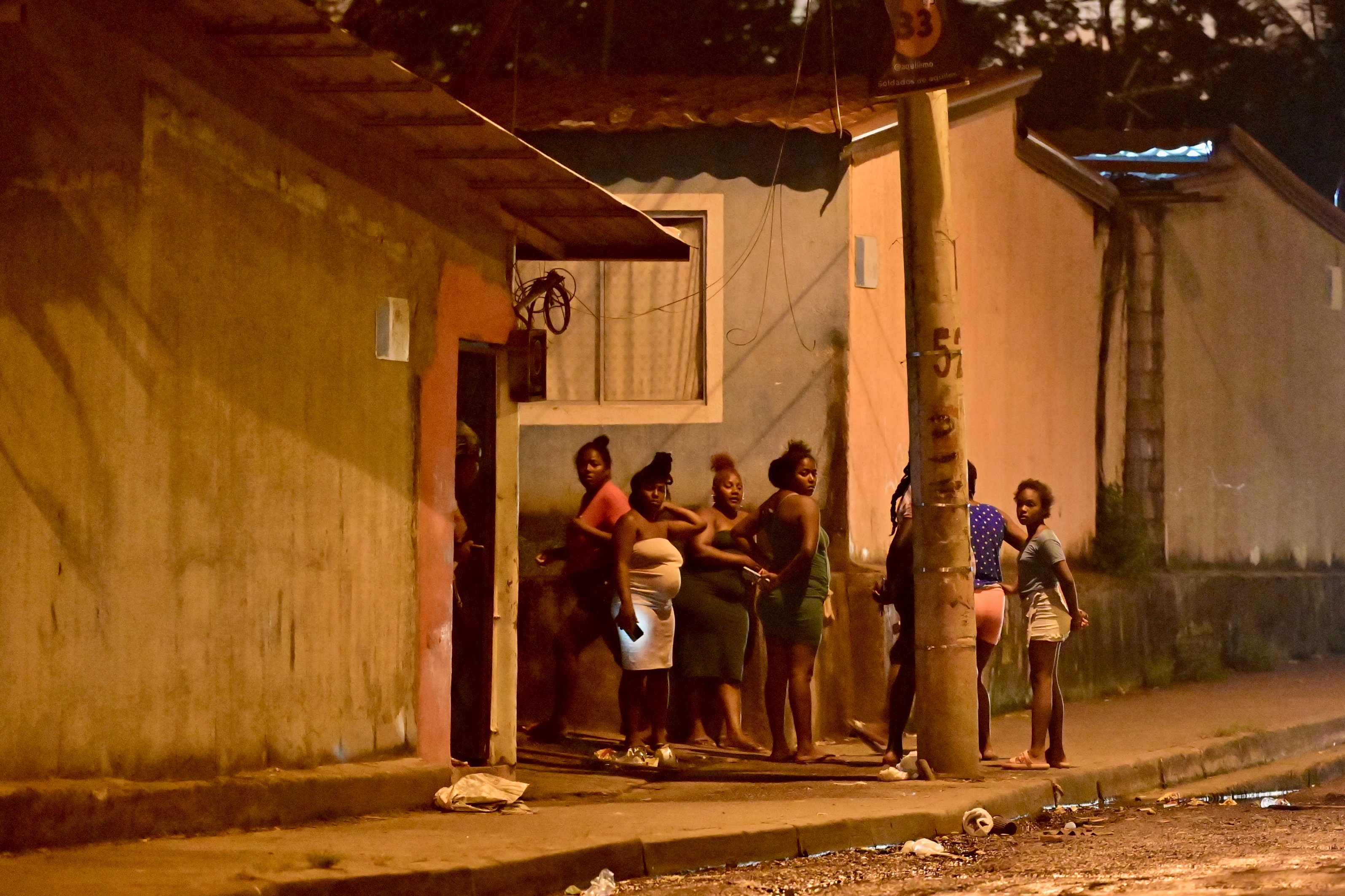 Women stand on a sidewalk close to a massacre site in Guayaquil.