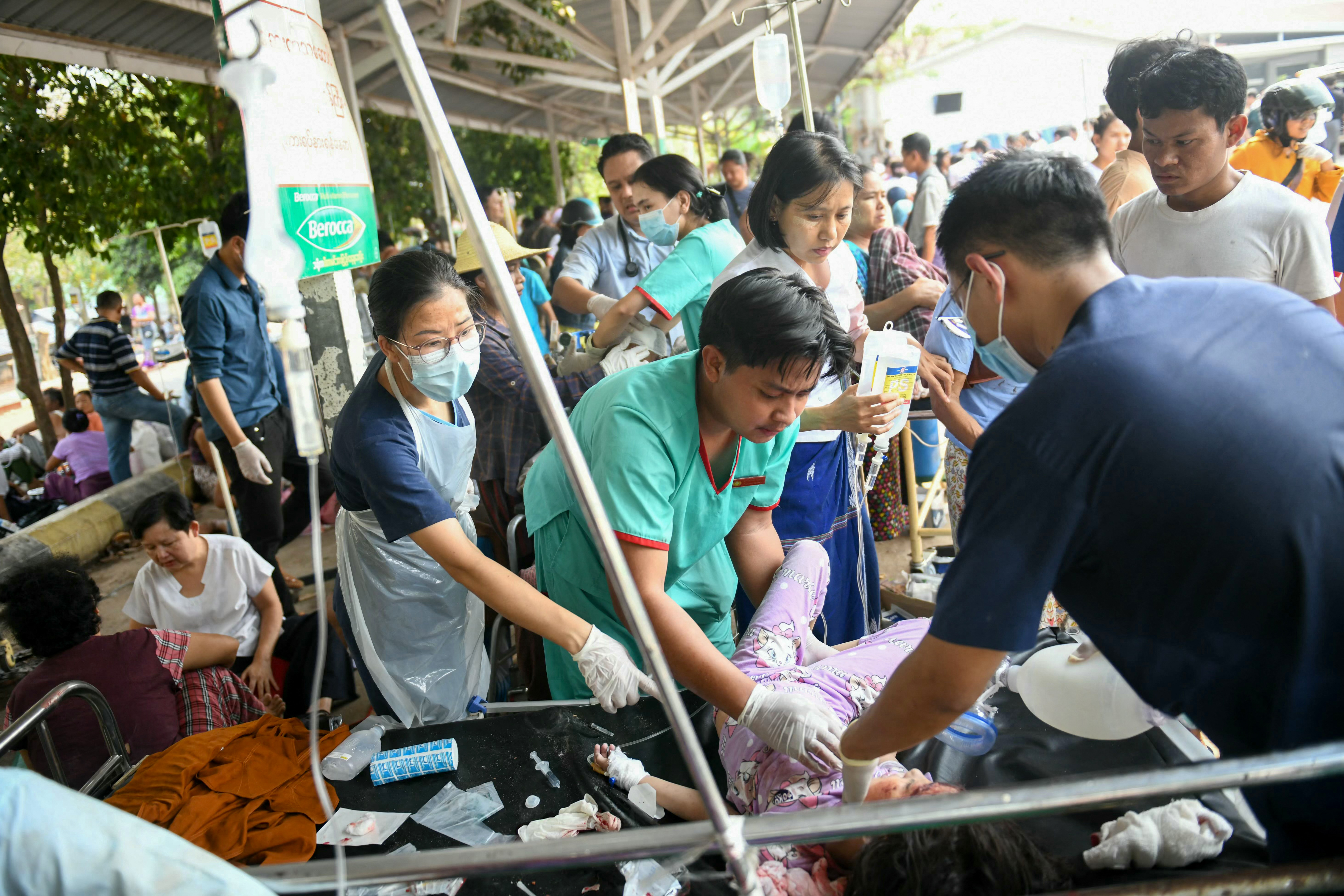 Medical workers treat a earthquake survivor on a bed in the compound of a hospital in Naypyidaw on March 28, 2025