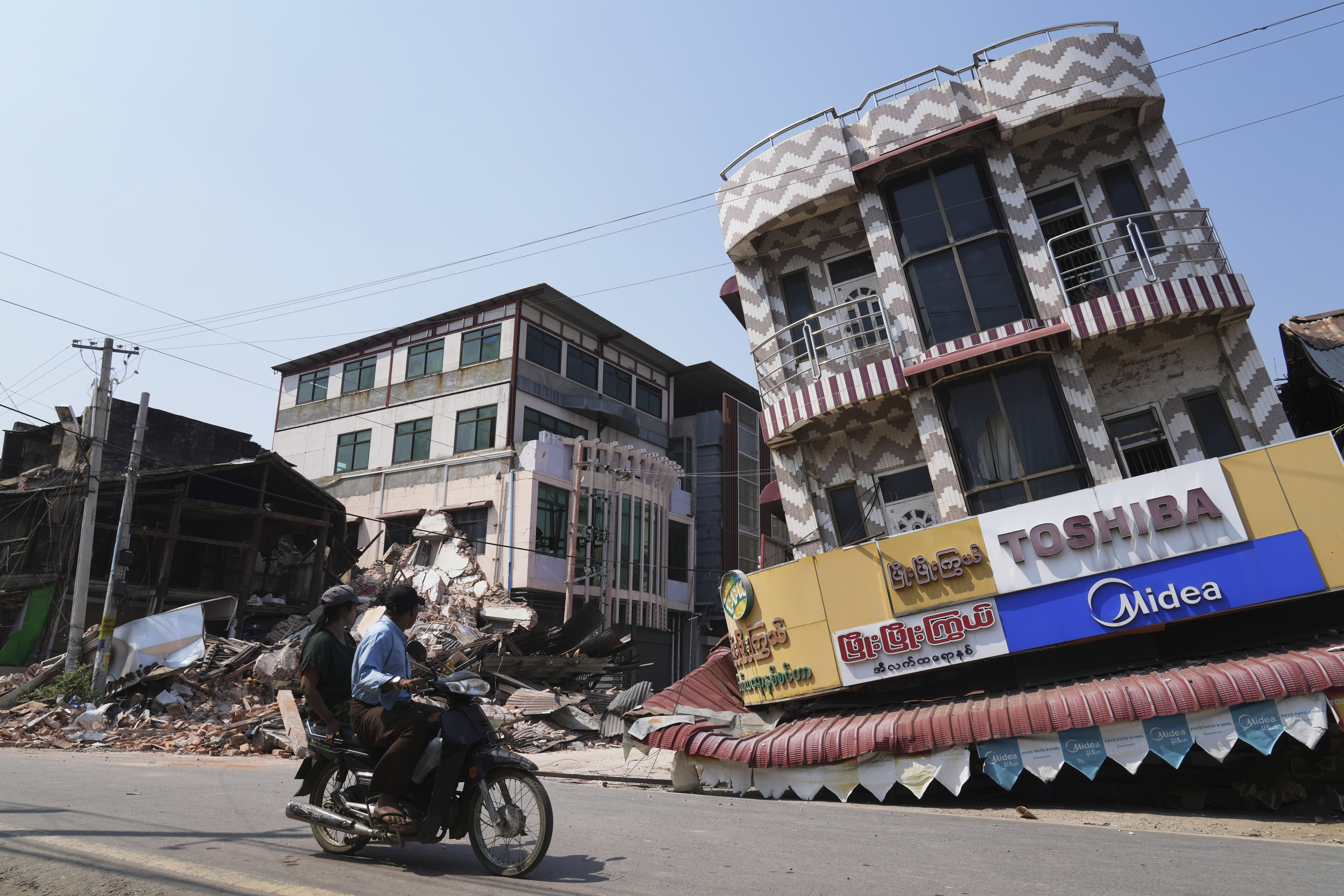 A local man drives a motorbike past a damaged building after an earthquake, in Naypyidaw
