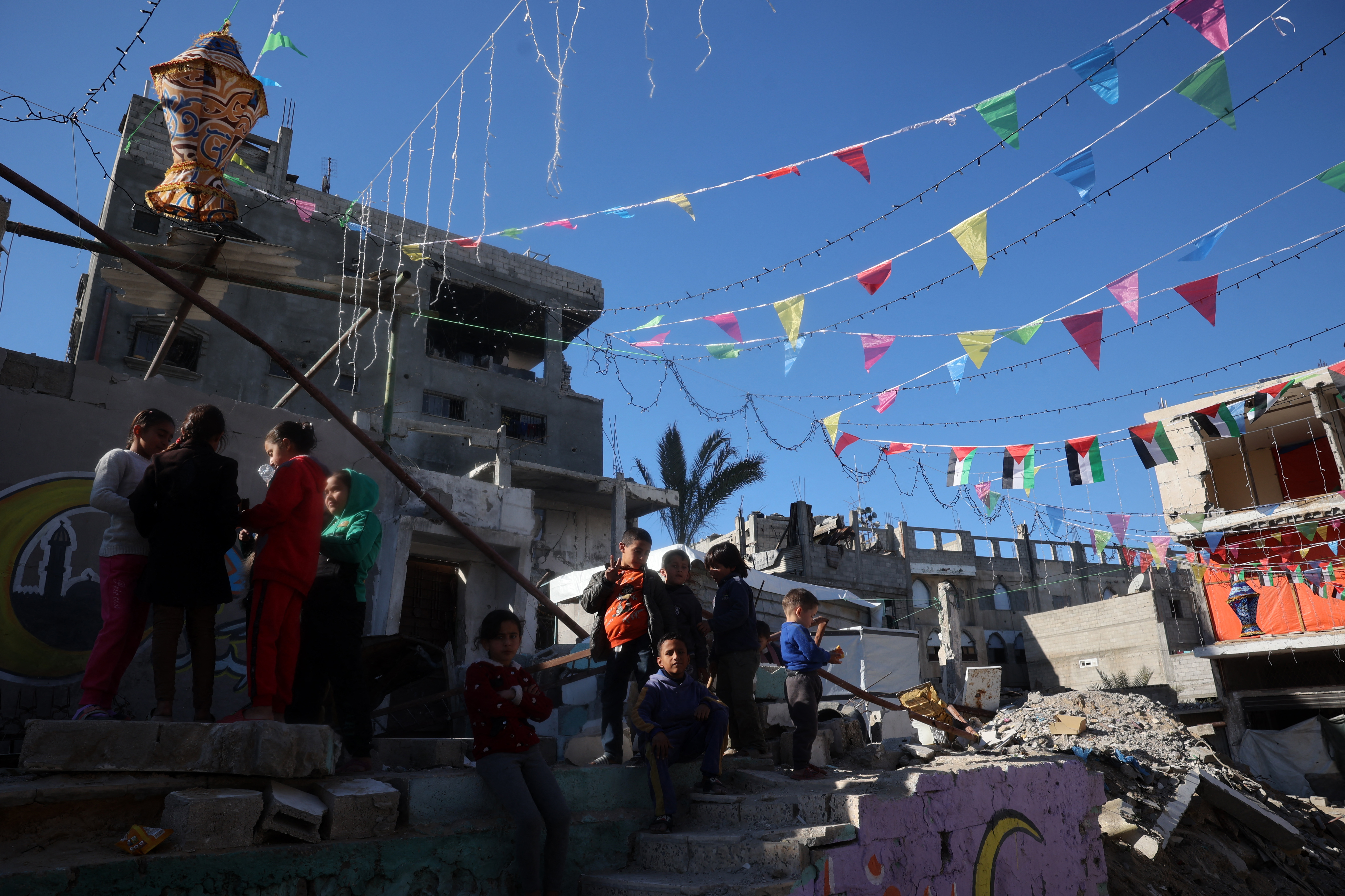 Children gather in a neighbourhood decorated ahead of the Muslim holy fasting month of Ramadan, in Khan Yunis in the southern Gaza Strip on February 28, 2025, amid the current ceasefire deal in the war between Israel and Hamas. (Photo by Eyad BABA / AFP)