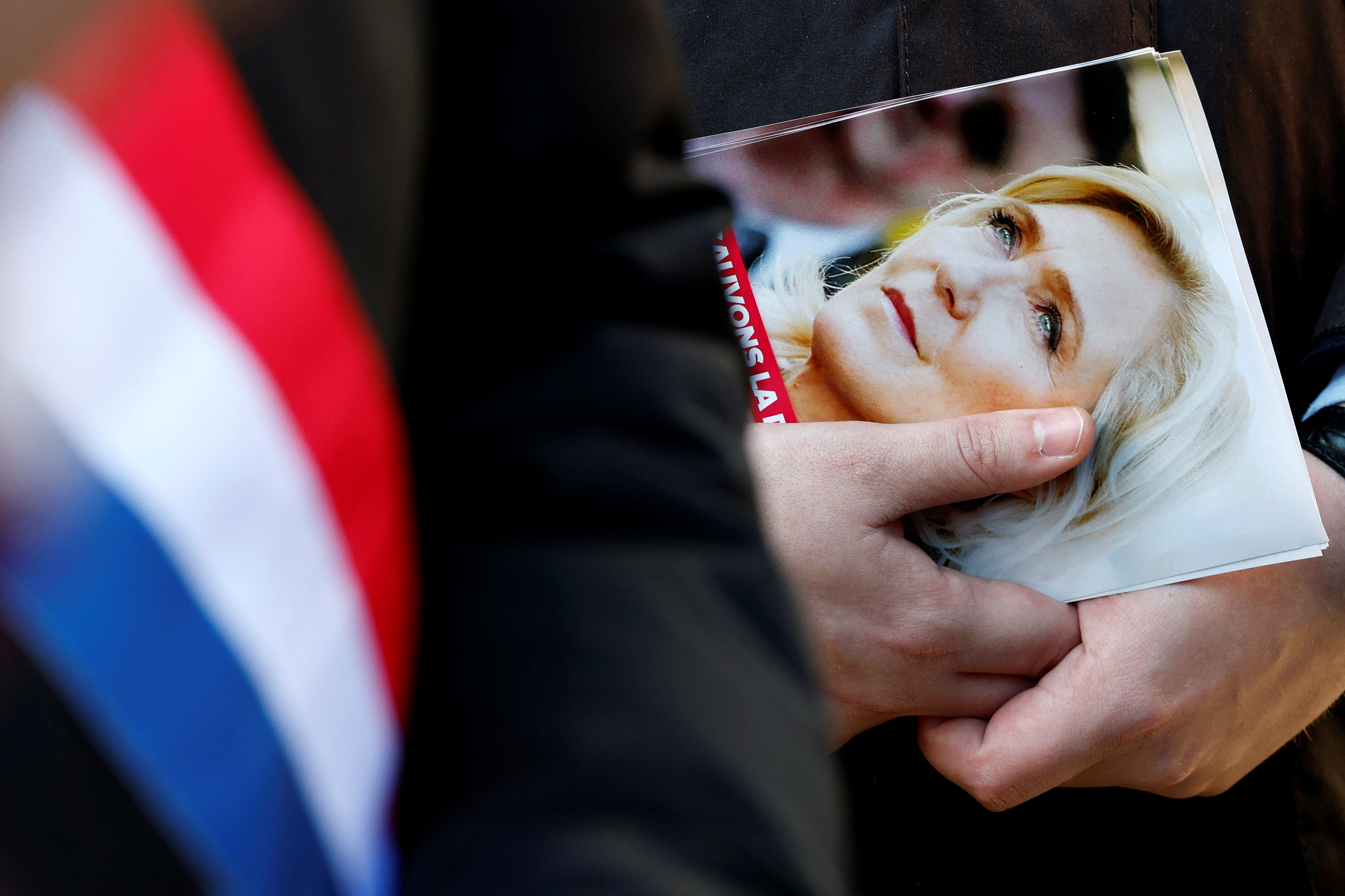 A local elected official from the French far-right National Rally party distributes leaflets in support of Marine Le Pen at a market in Henin-Beaumont, France